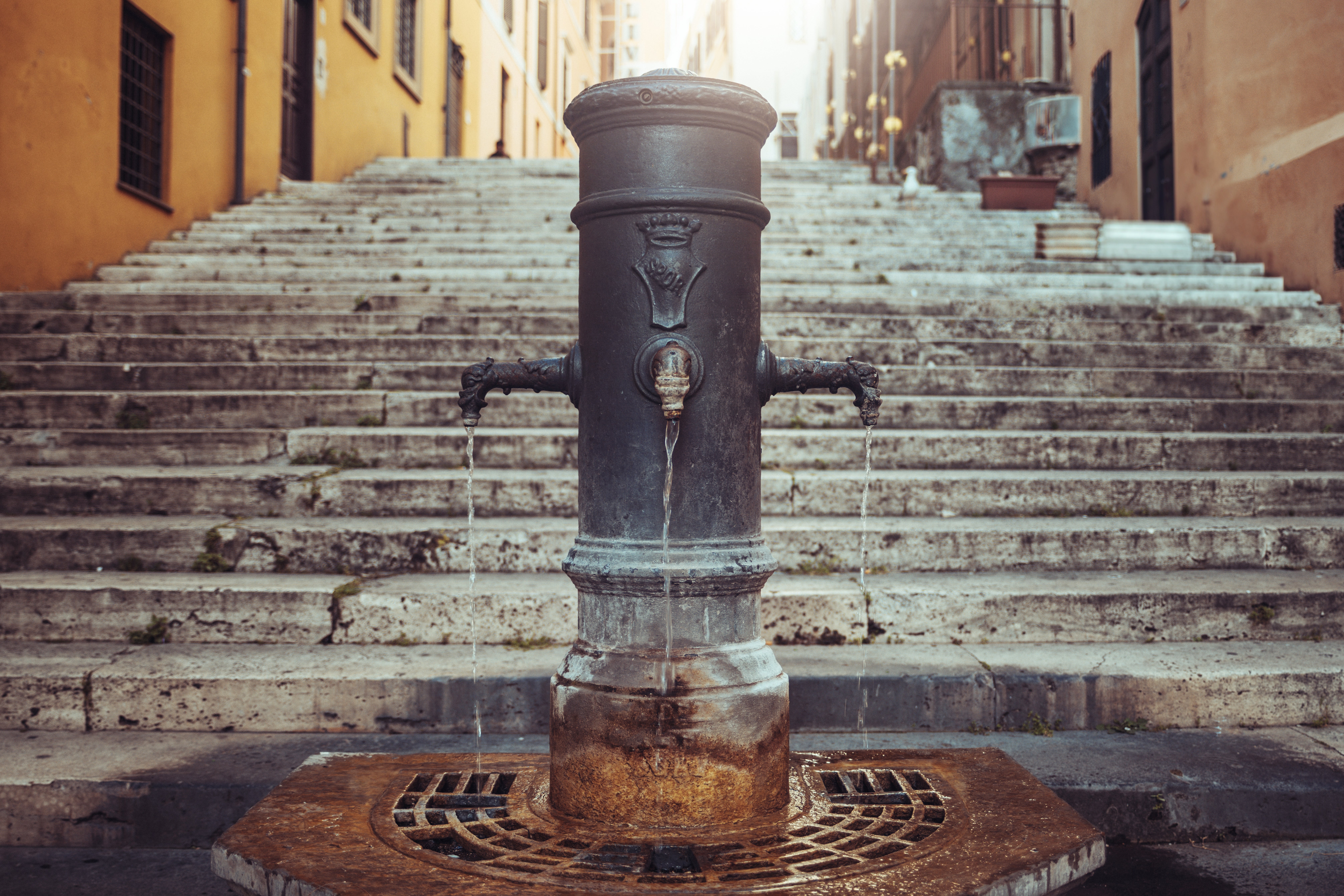 Stone fountain with ornate design, surrounded by weathered chromatic stairs successful a historical European thoroughfare setting