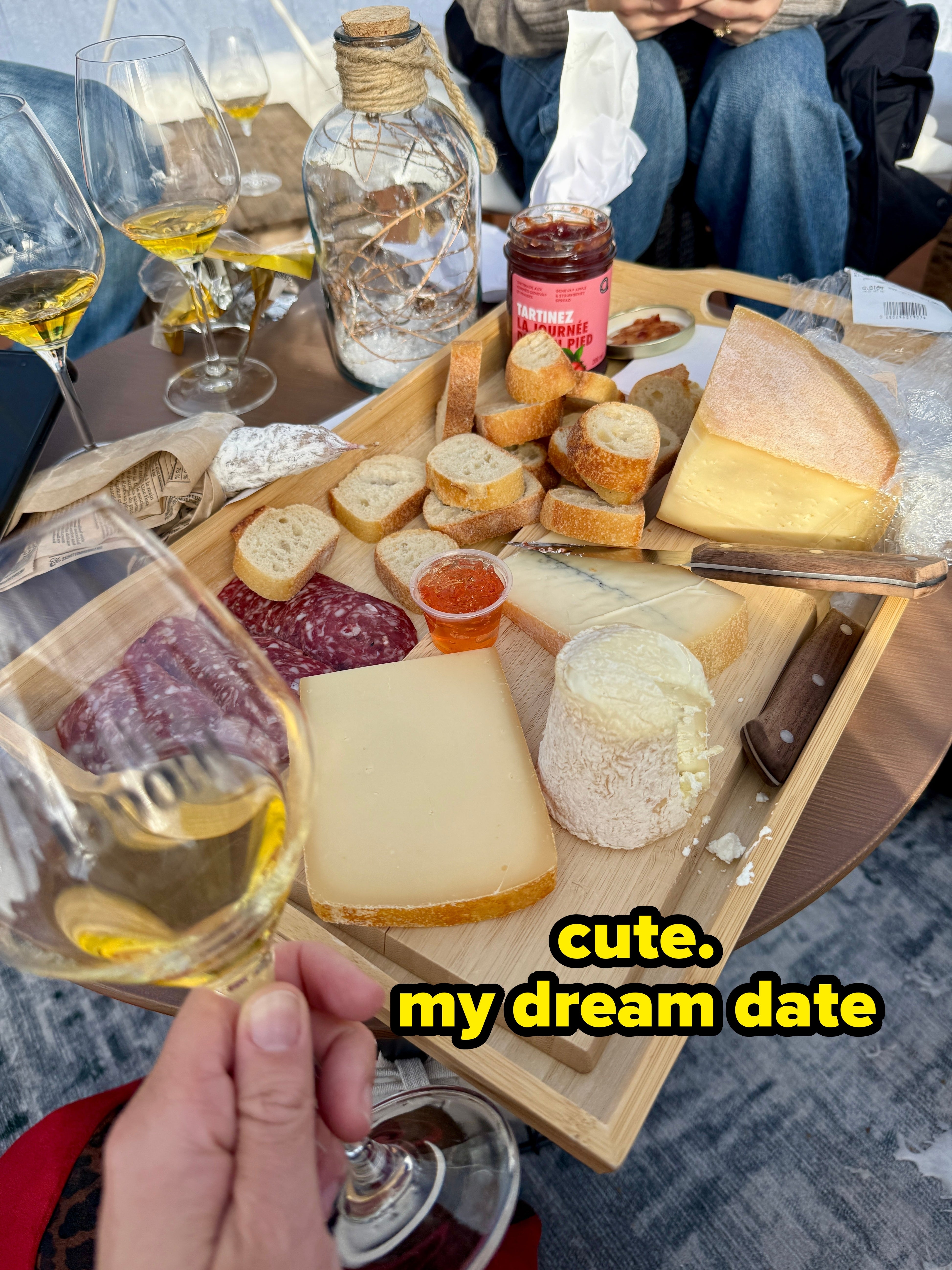 A vino and food tasting setup with assorted cheeses, sliced baguette, and vino glasses connected a woody board, evoking a cozy question experience