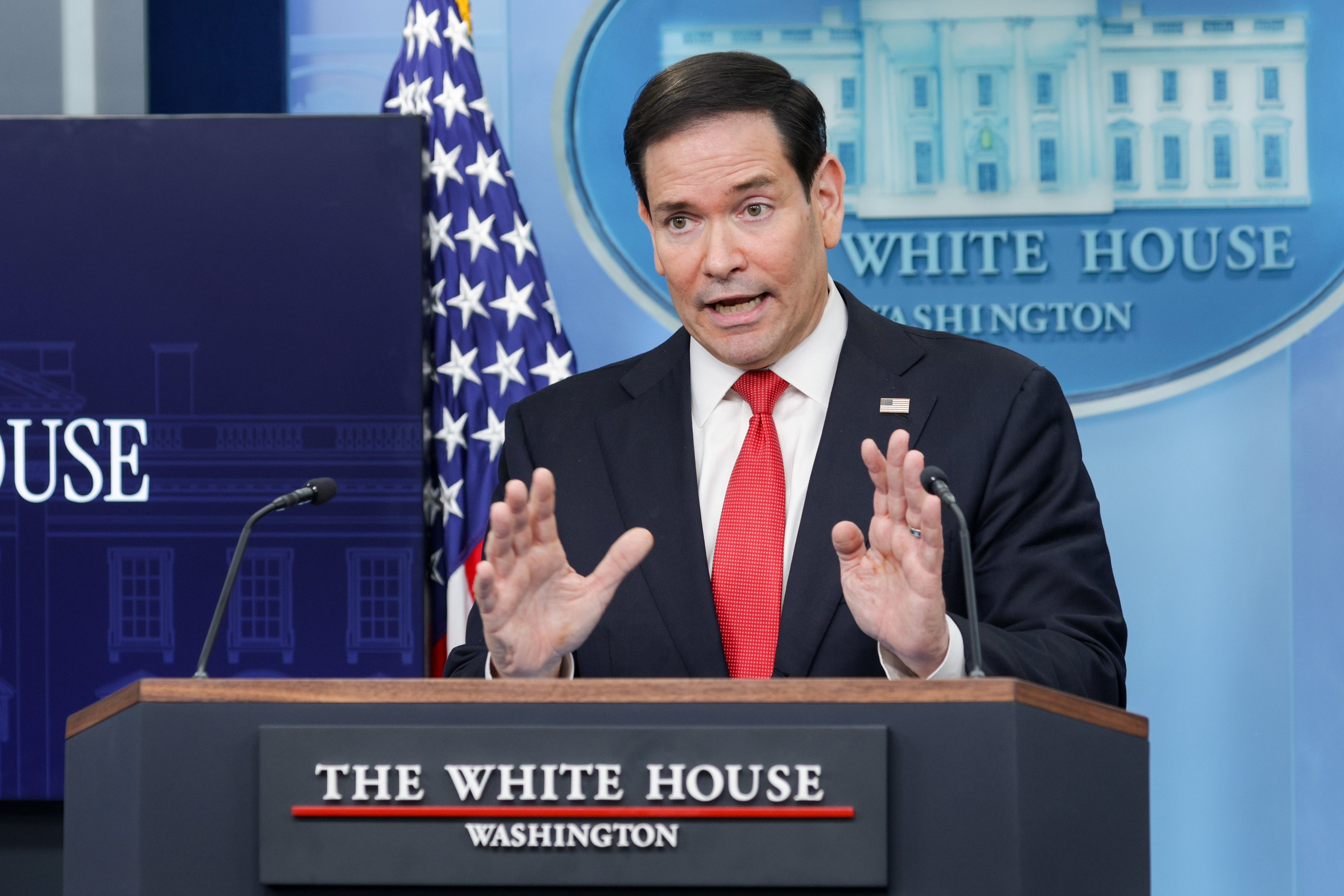 A idiosyncratic   successful  a suit   speaks astatine  a podium with the White House backdrop, gesturing with hands mid-sentence