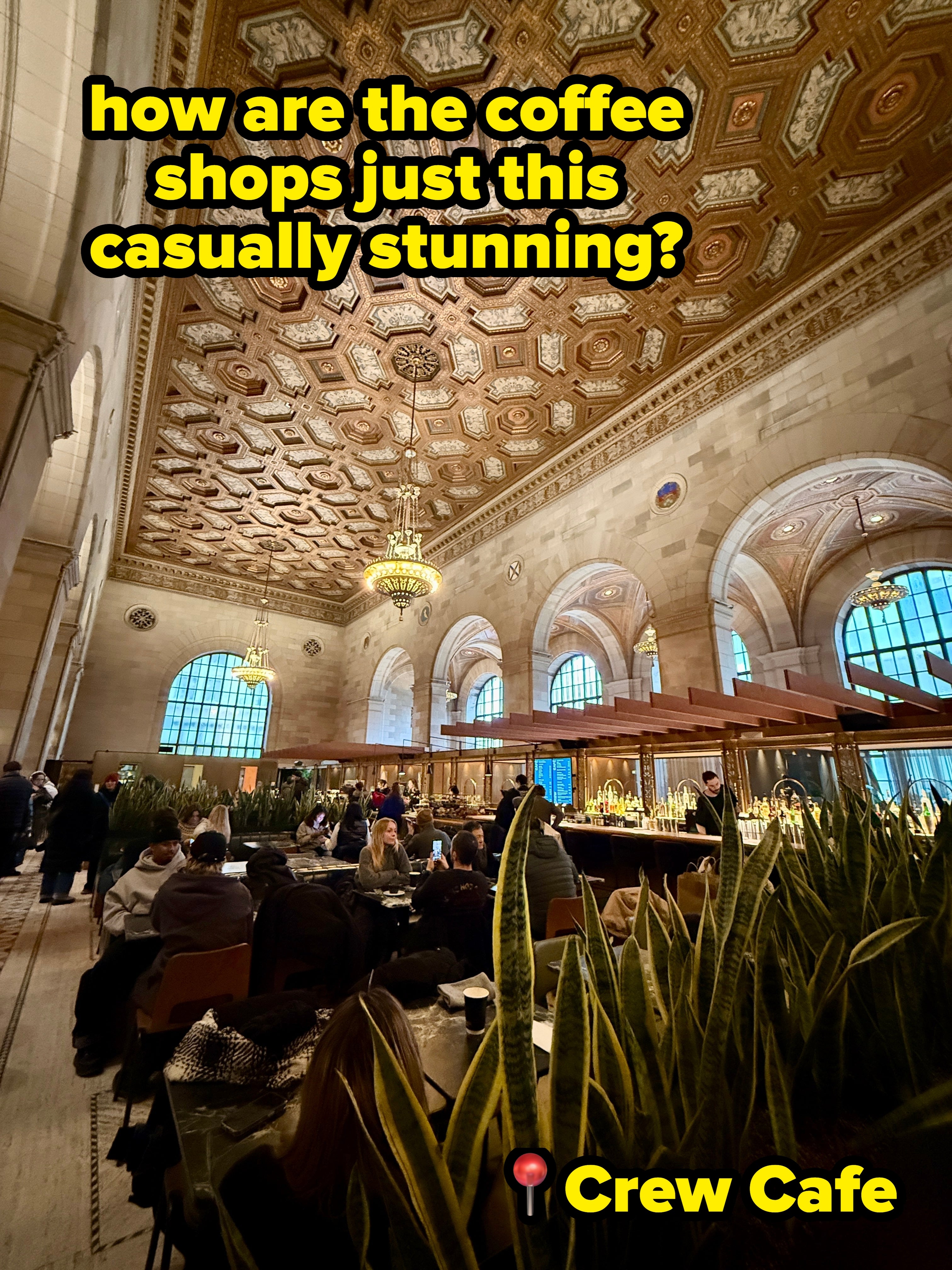People eating successful a expansive hallway with an ornate ceiling, ample windows, and elegant chandeliers, enhancing the luxurious atmosphere