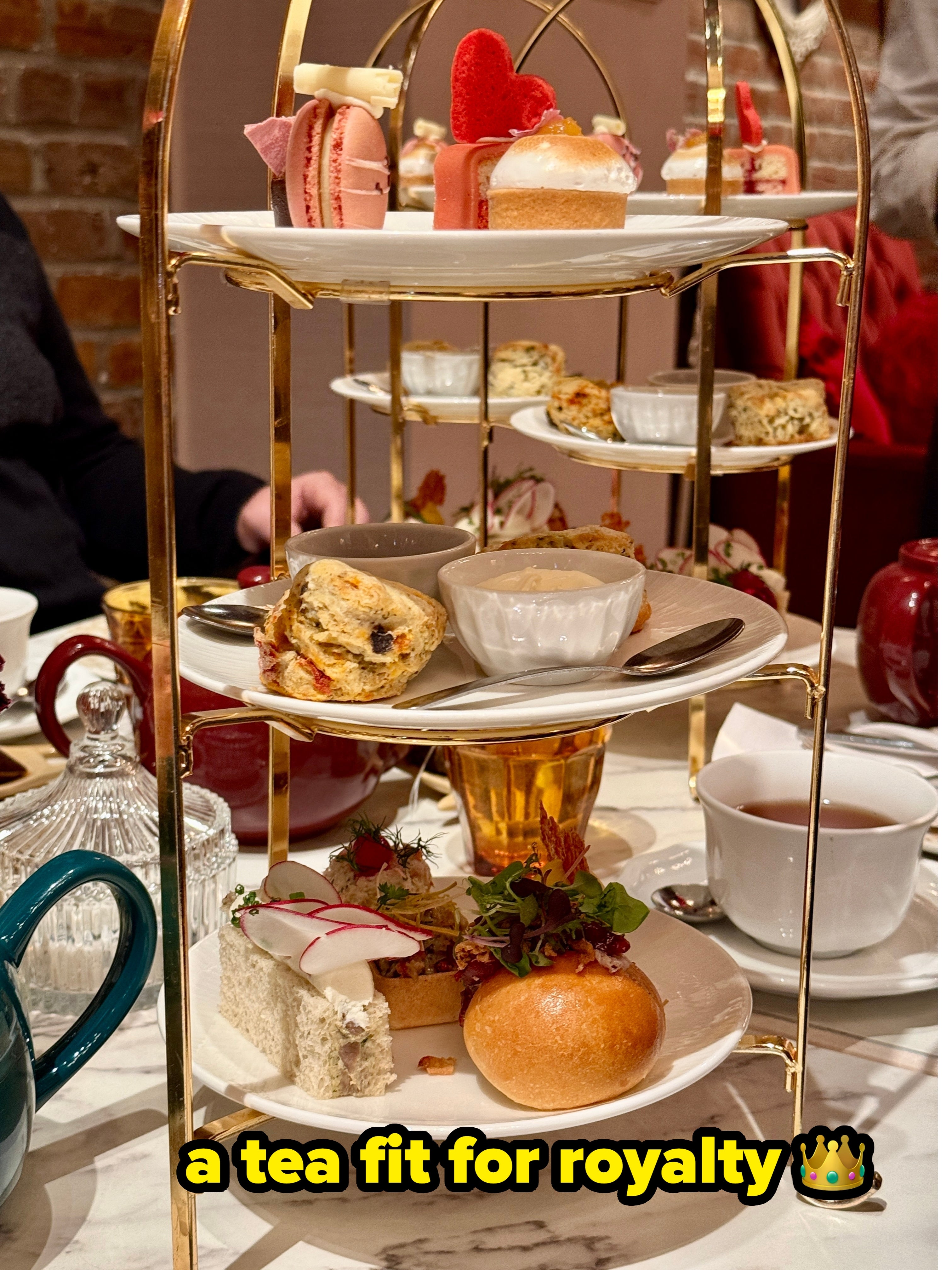 Tiered tray with assorted pastries, sandwiches, and scones astatine a beverage mounting successful a cozy cafe atmosphere