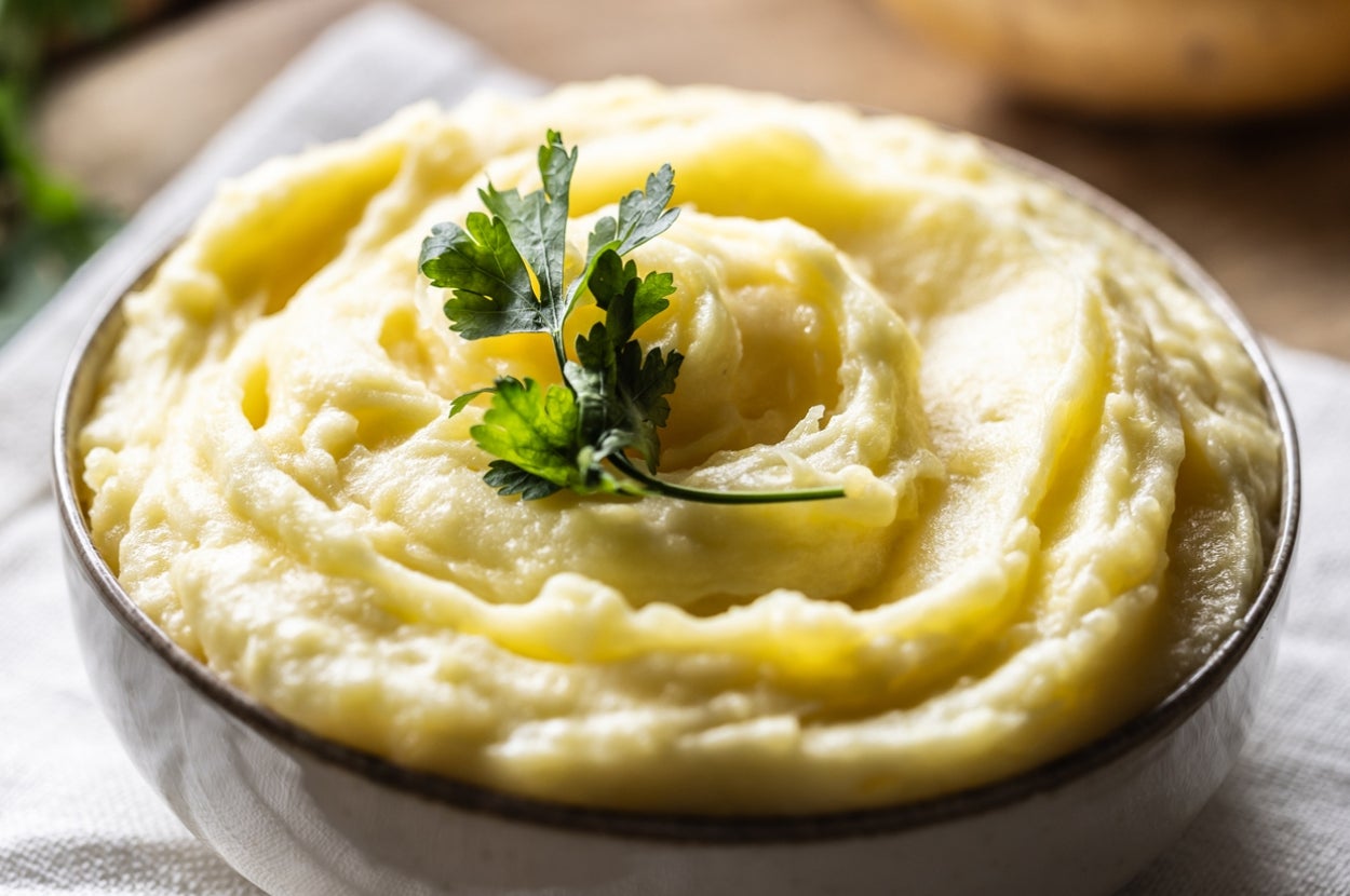 A bowl of creamy mashed potatoes topped with a sprig of parsley