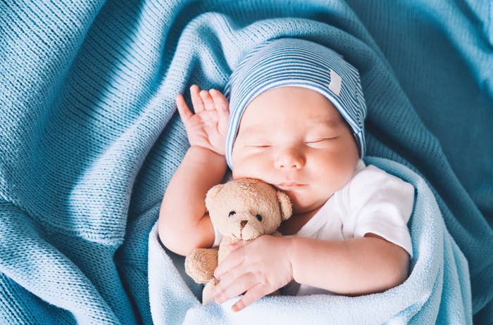 Baby sleeping peacefully, wrapped successful  a blanket, holding a tiny  teddy bear