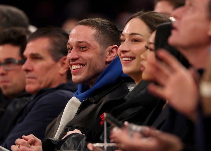 People sitting and smiling at an event, wearing casual and semi-formal attire
