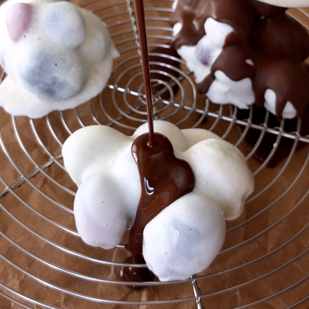 チョコレートが白いクッキーの上にかけられているシーン。食欲をそそるデザートの一瞬。