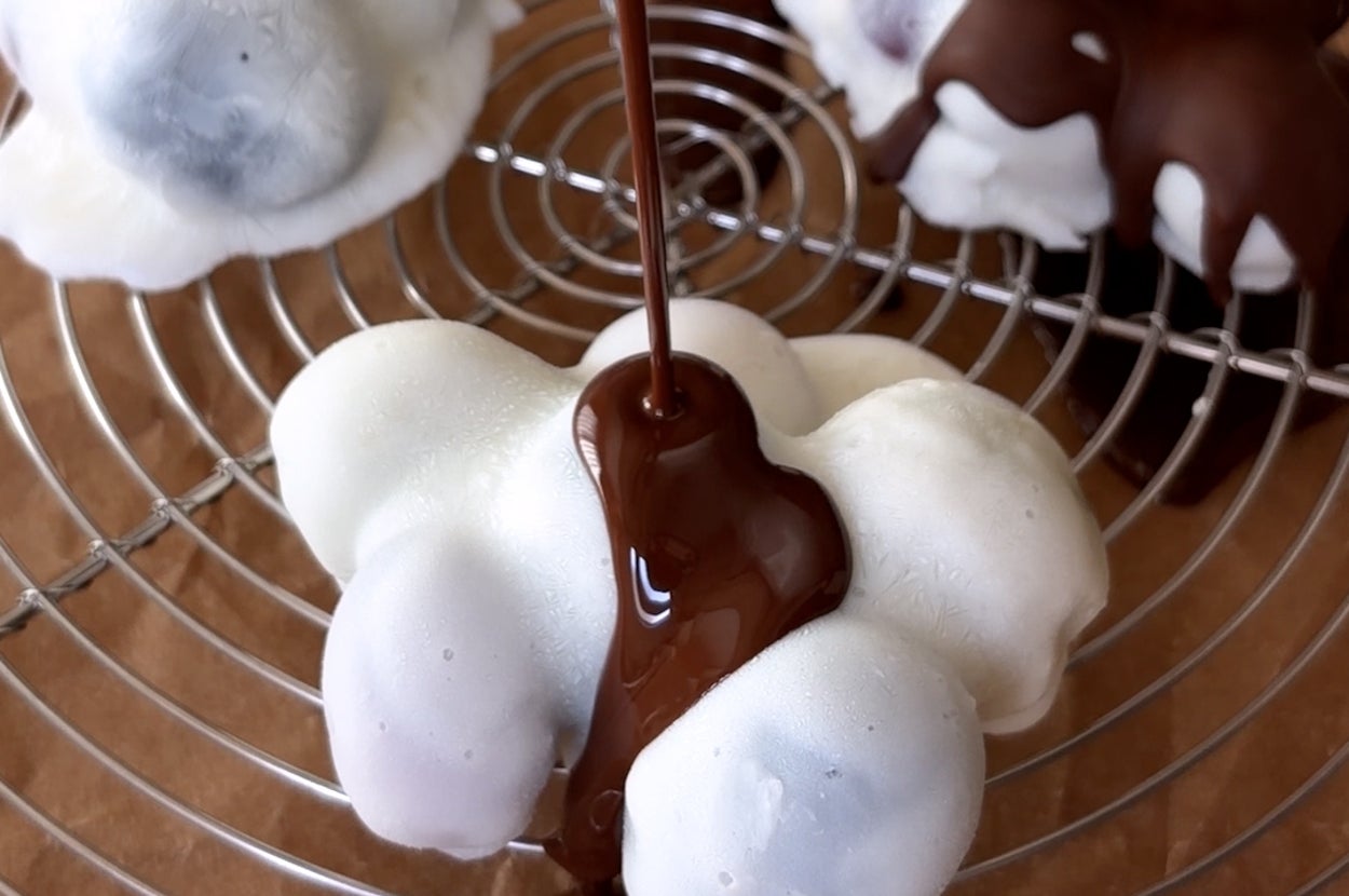 チョコレートが白いクッキーの上にかけられているシーン。食欲をそそるデザートの一瞬。