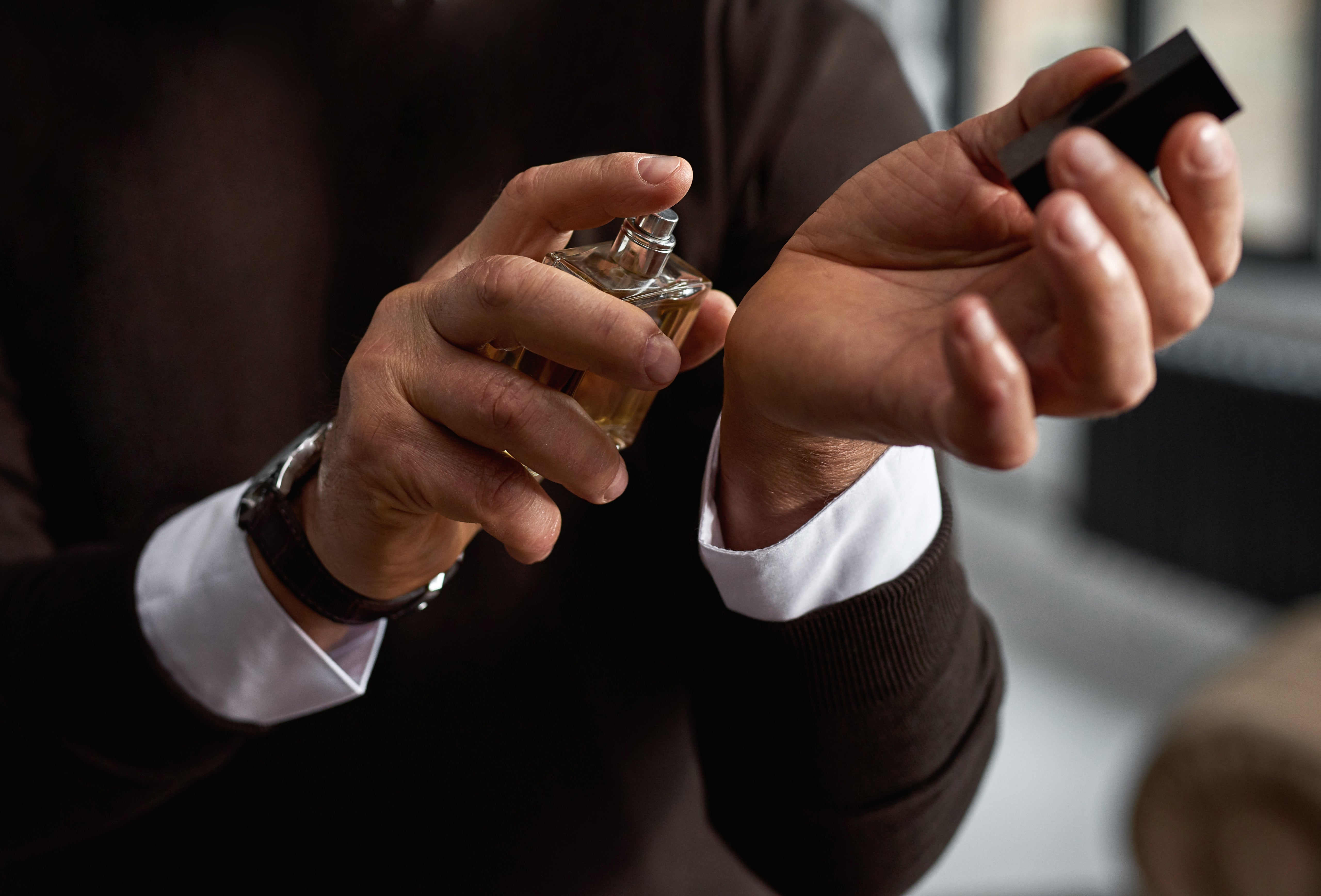 Older antheral applying cologne to his wrist wrong a modern room