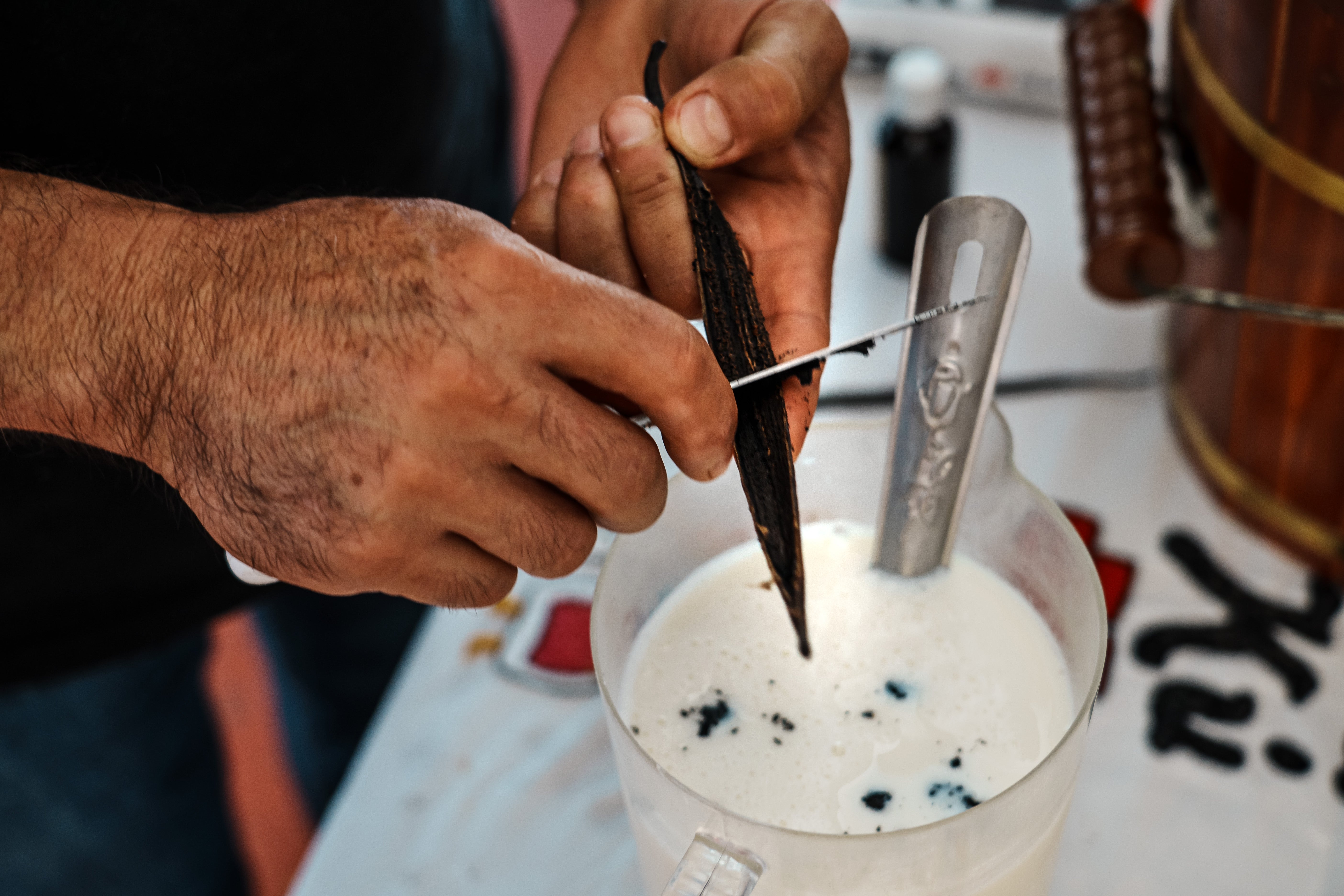 Person slicing a vanilla legume implicit a mixing instrumentality filled with a creamy liquid, preparing ingredients for a recipe
