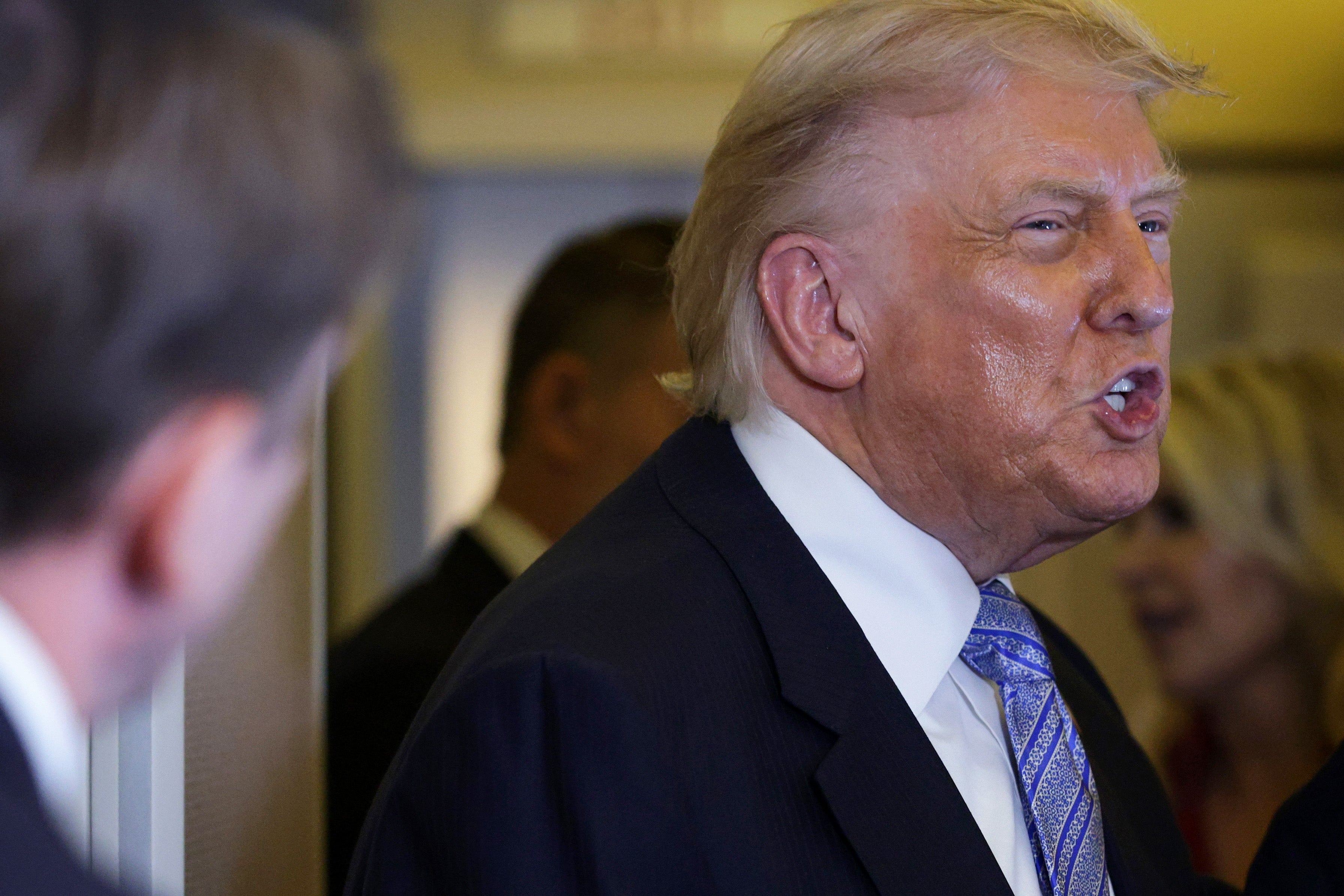 A person in a suit with a striped tie is speaking to another person in a professional setting