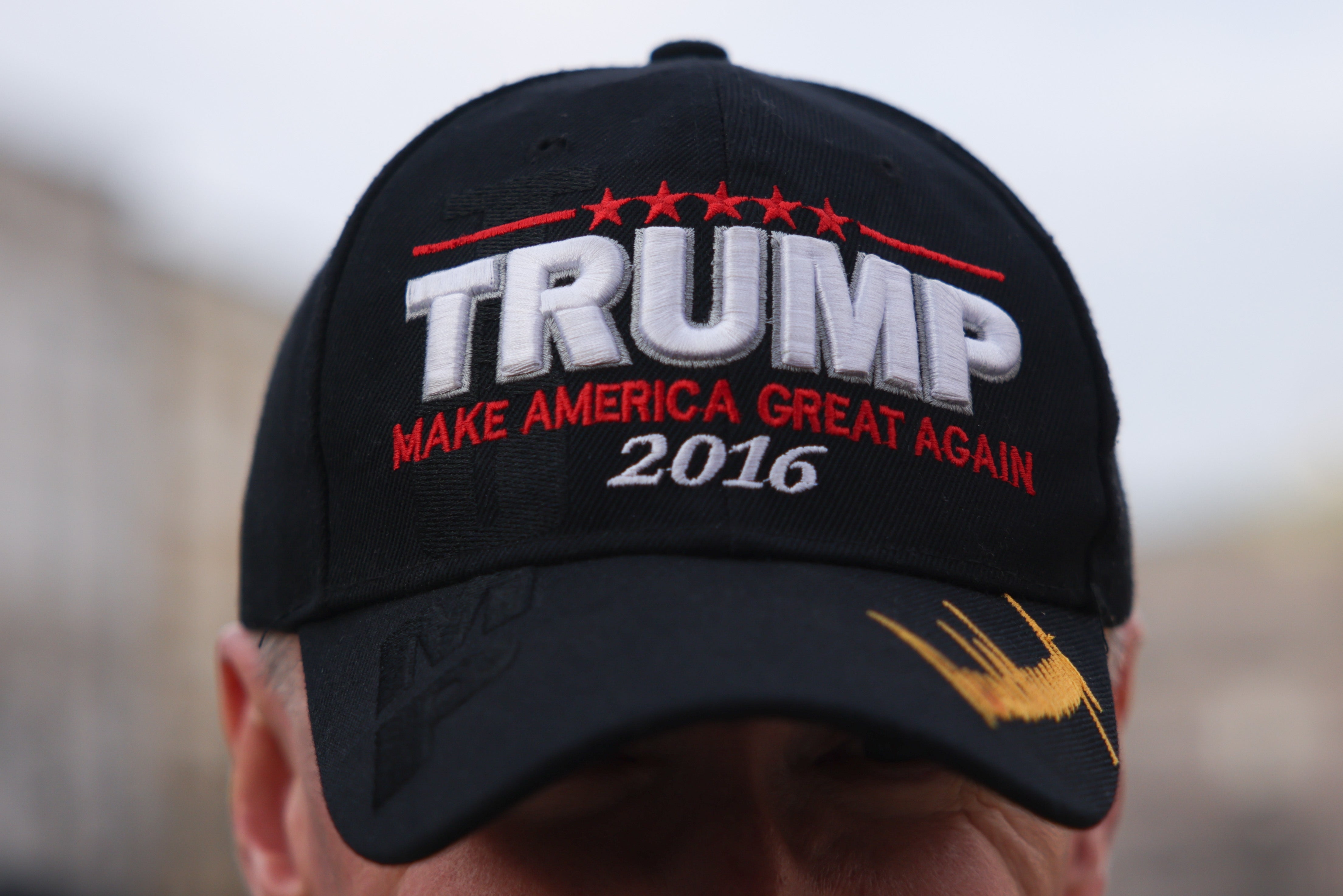 Person wearing a black cap with "TRUMP MAKE AMERICA GREAT AGAIN 2016" embroidered on it