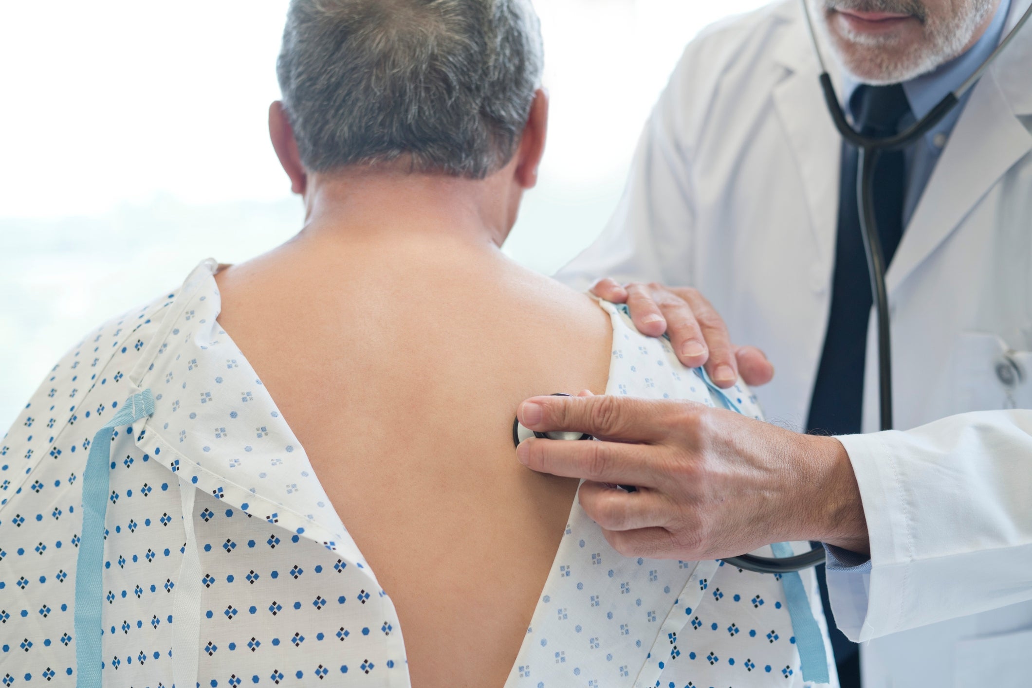 Doctor listens to a patient's breathing with a stethoscope on their back, illustrating a medical checkup