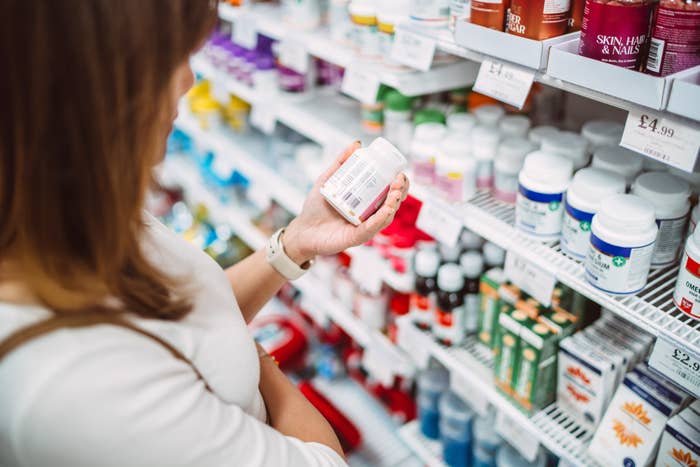 Person examines a vessel  of supplements successful  a store   aisle filled with assorted  wellness  products