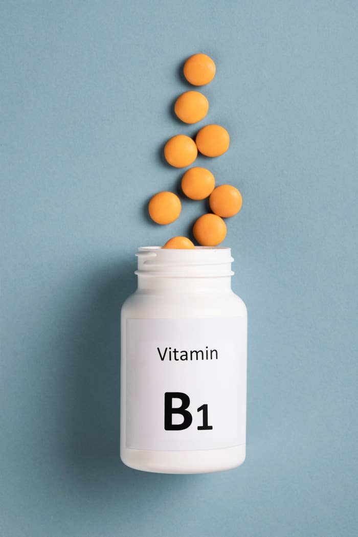 Vitamin B1 tablets spilling from a achromatic  vessel  connected  a level  surface