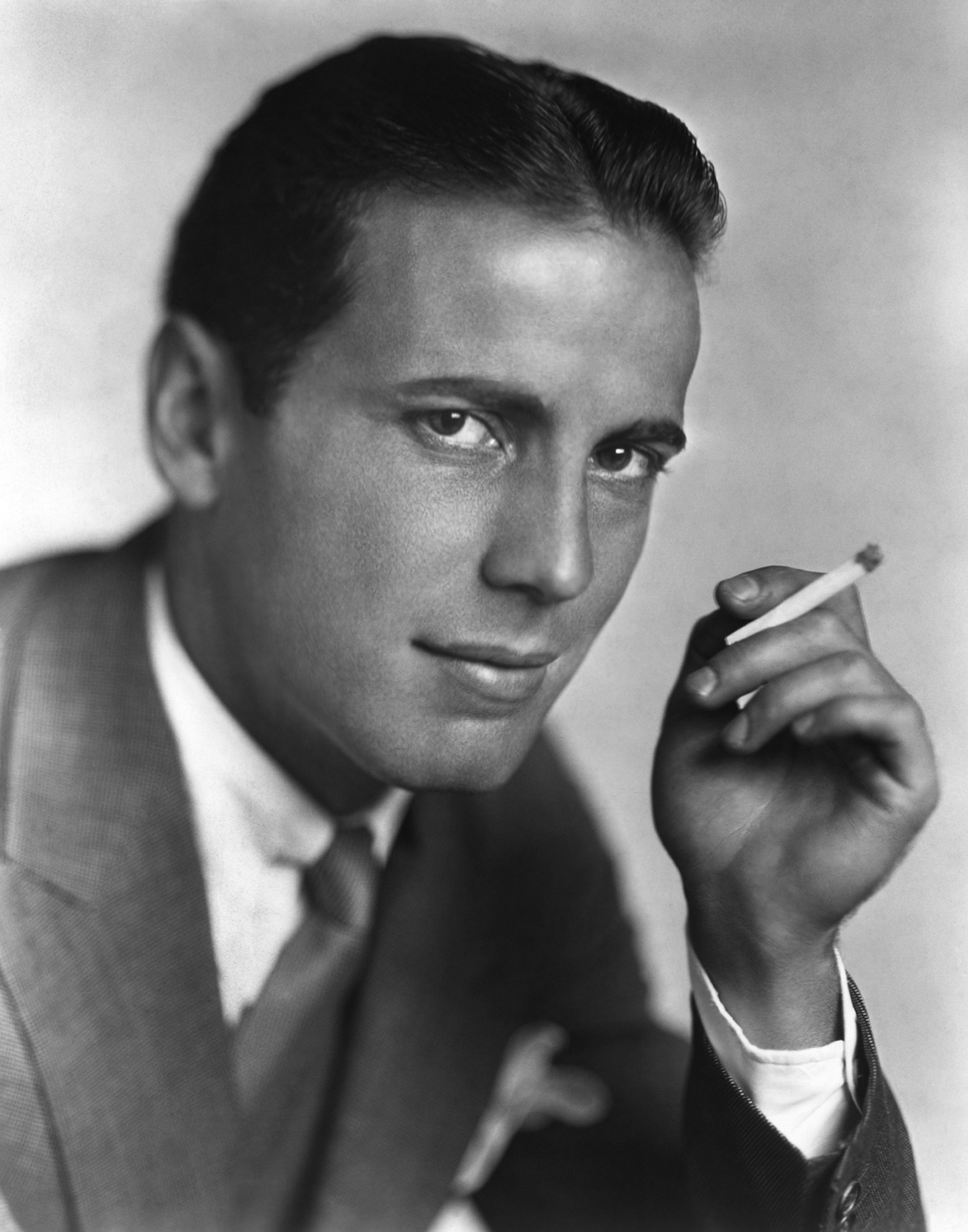 Humphrey Bogart poses for a portrait with a cigarette in hand