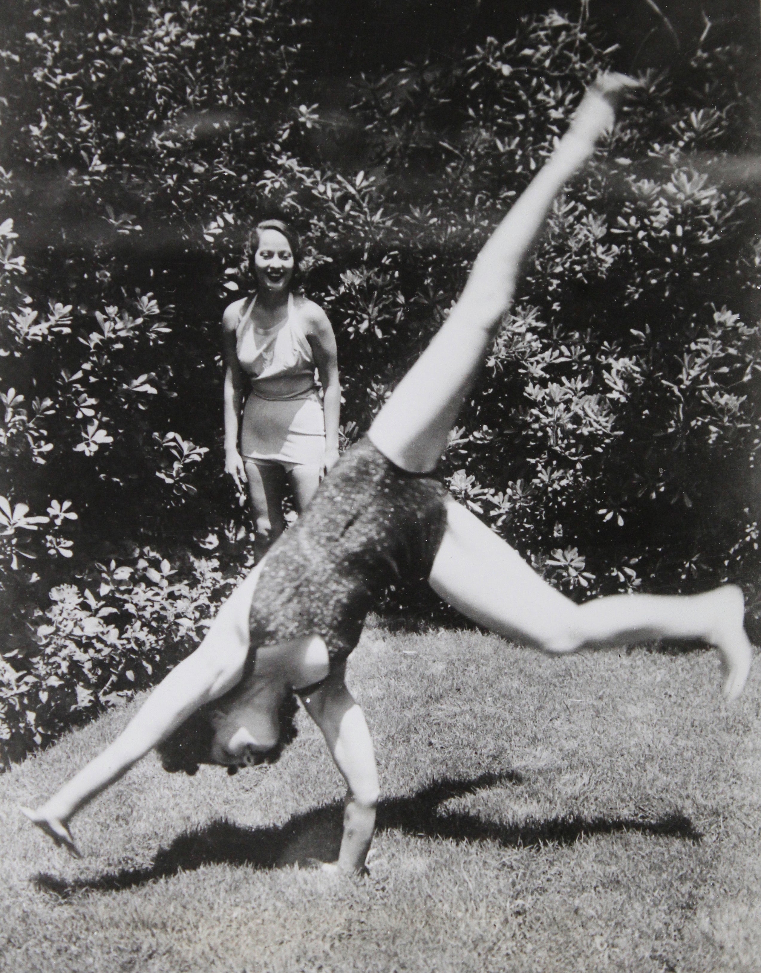Norma Shearer doing cartwheels in her garden while Merle Oberon watches