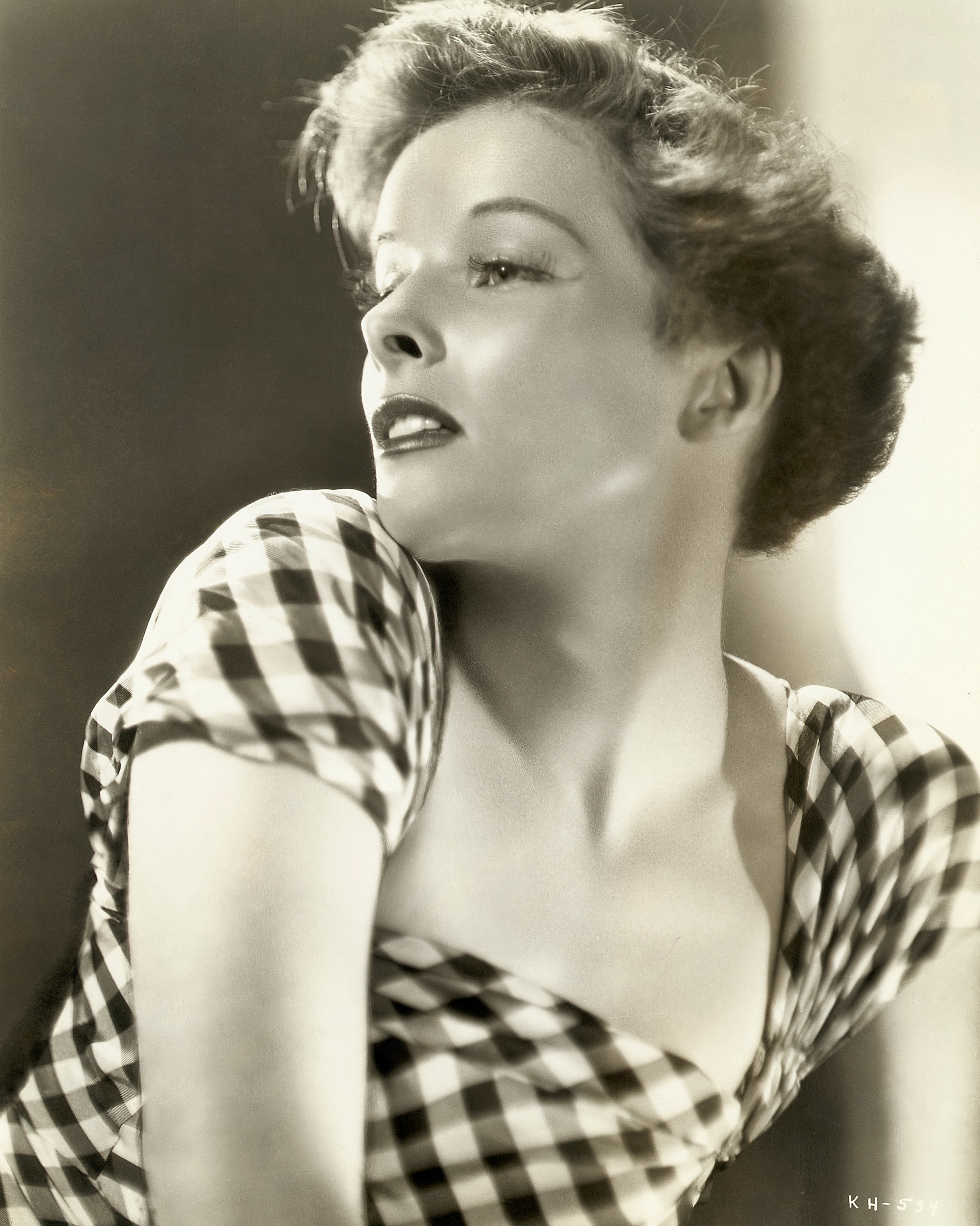Katharine Hepburn in checkered dress gazing to the side in a classic, elegant pose
