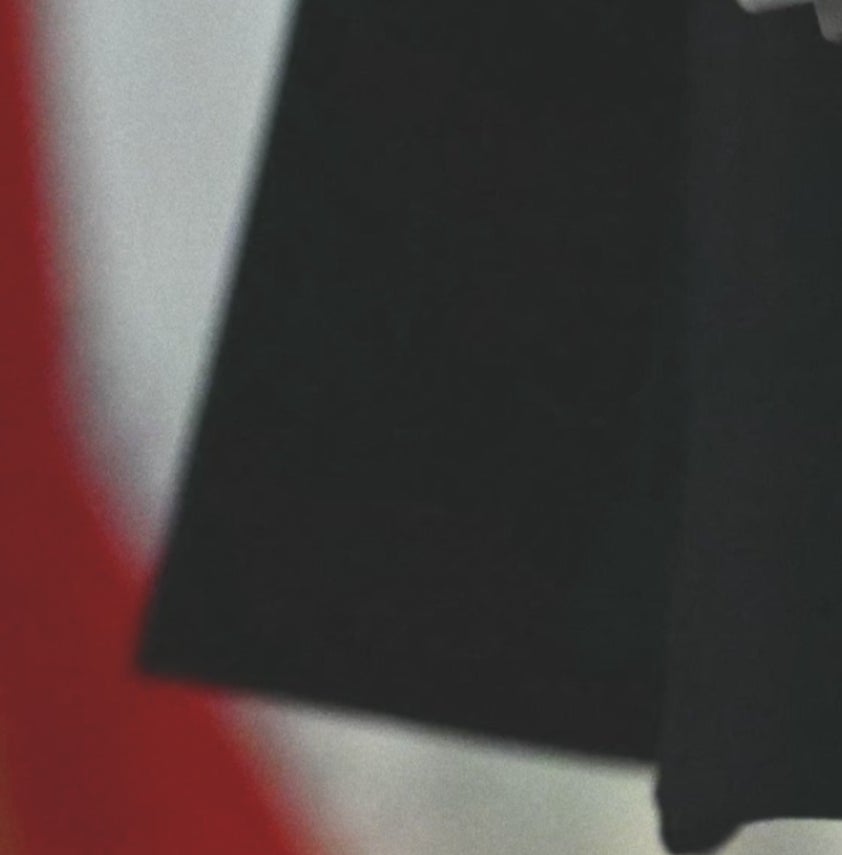 Closer close up of a dark red, hairy, and bruised hand that sticks out from a striped suit jacket in front of an American flag background