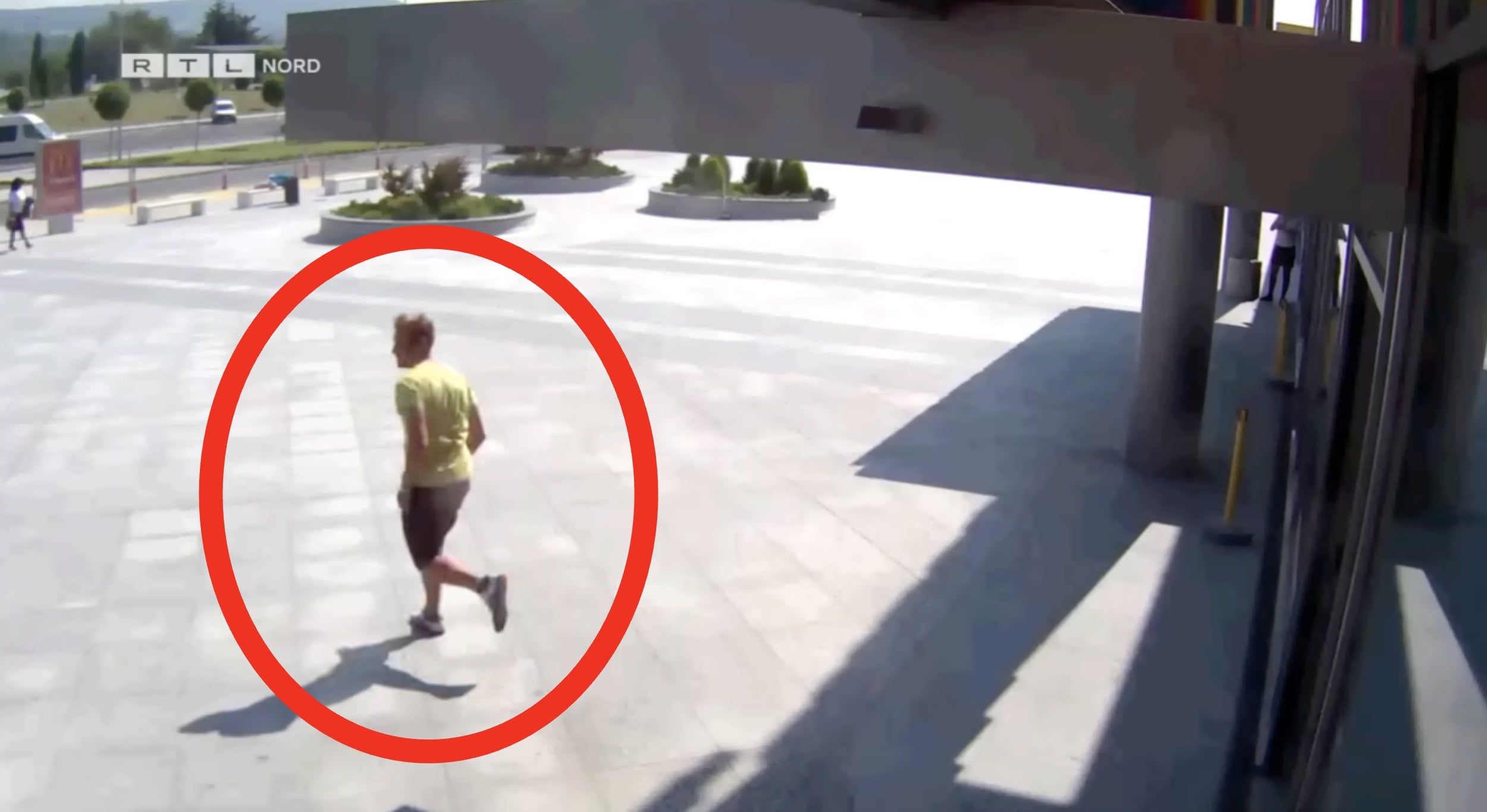 Person walking outdoors is circled in red in a security camera footage