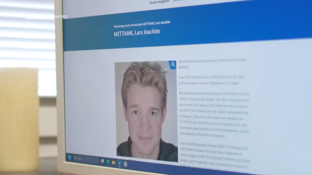A laptop screen displays a webpage about a missing person named Lars Mittank. It includes his photo and descriptive text