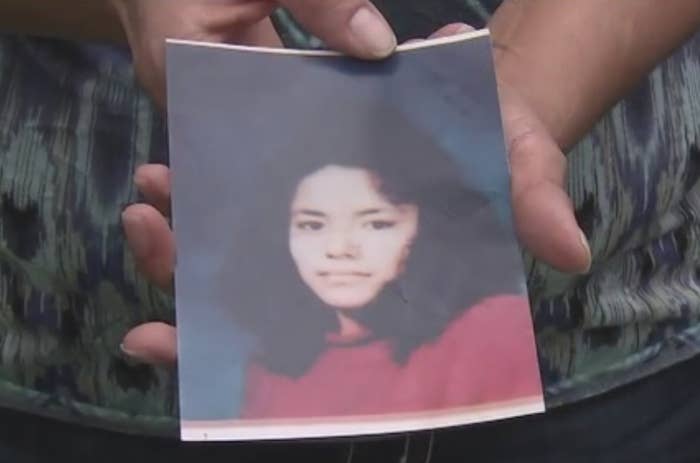 Person holding a photograph  of a young pistillate   wearing a sweater, looking toward the camera