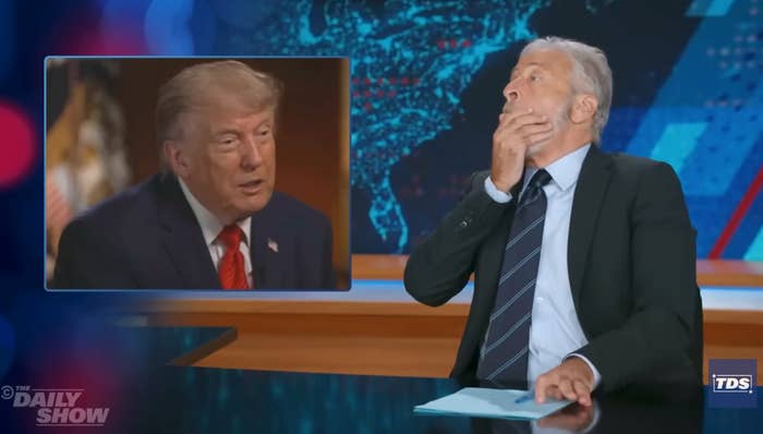 TV host reacts humorously while watching a video of a political figure on a news talk show set