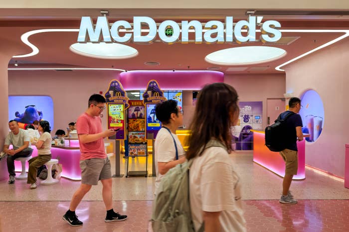 People walk past a McDonald's with bright pink interior and gaming machines, creating a vibrant, modern atmosphere