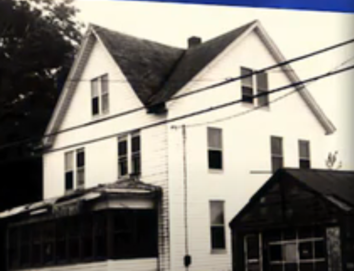 A large, multi-story location   with a peaked extortion   and a screened porch, acceptable   against trees successful  the background