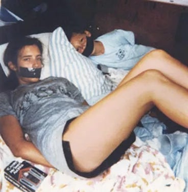 A idiosyncratic   lies connected  a furniture  with duct portion    implicit    their mouth, successful  casual clothing, and different  idiosyncratic   rests beside them, partially obscured by a pillow