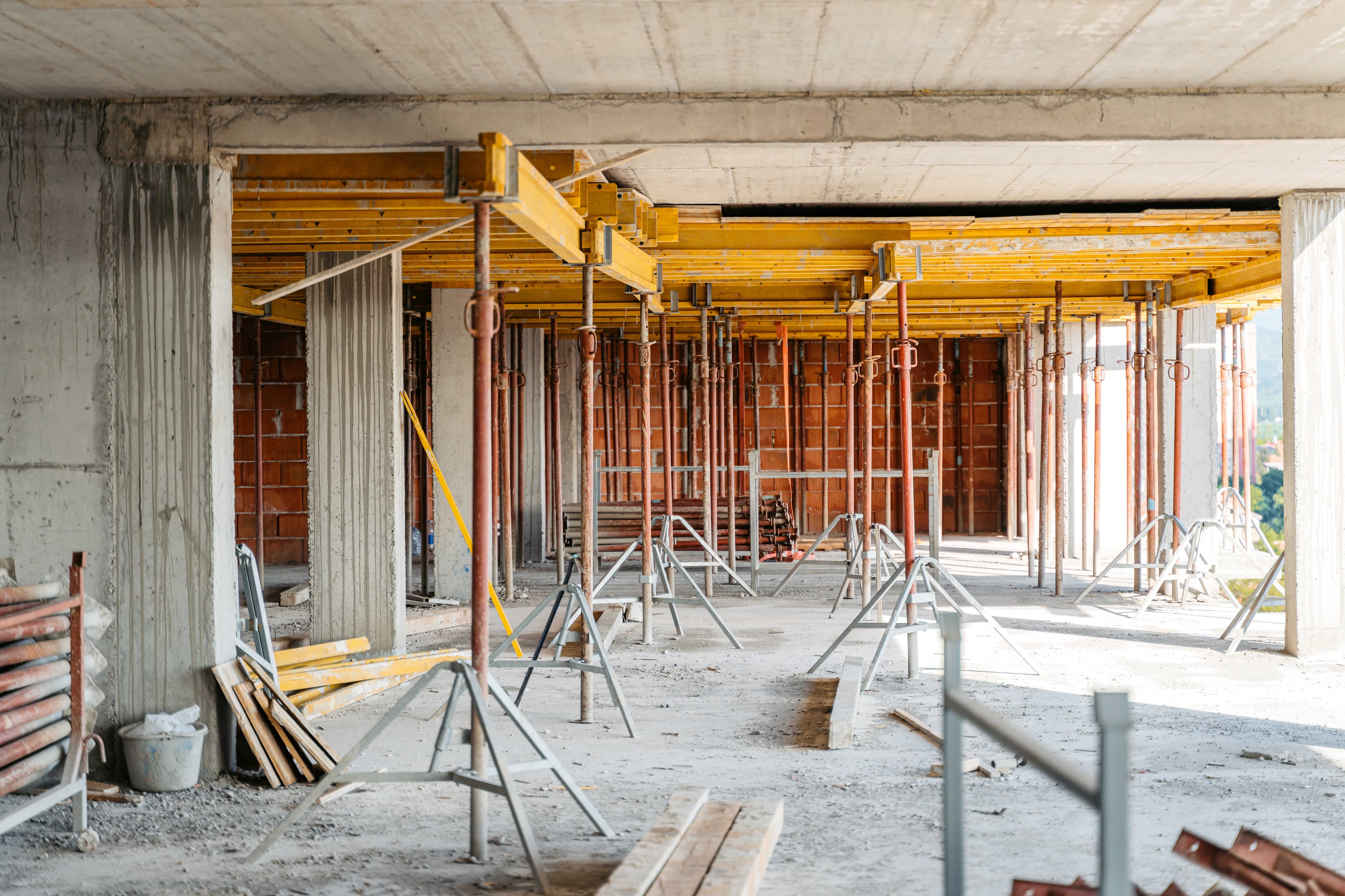 Construction site with metal and wooden scaffolding supporting a concrete ceiling in an unfinished building