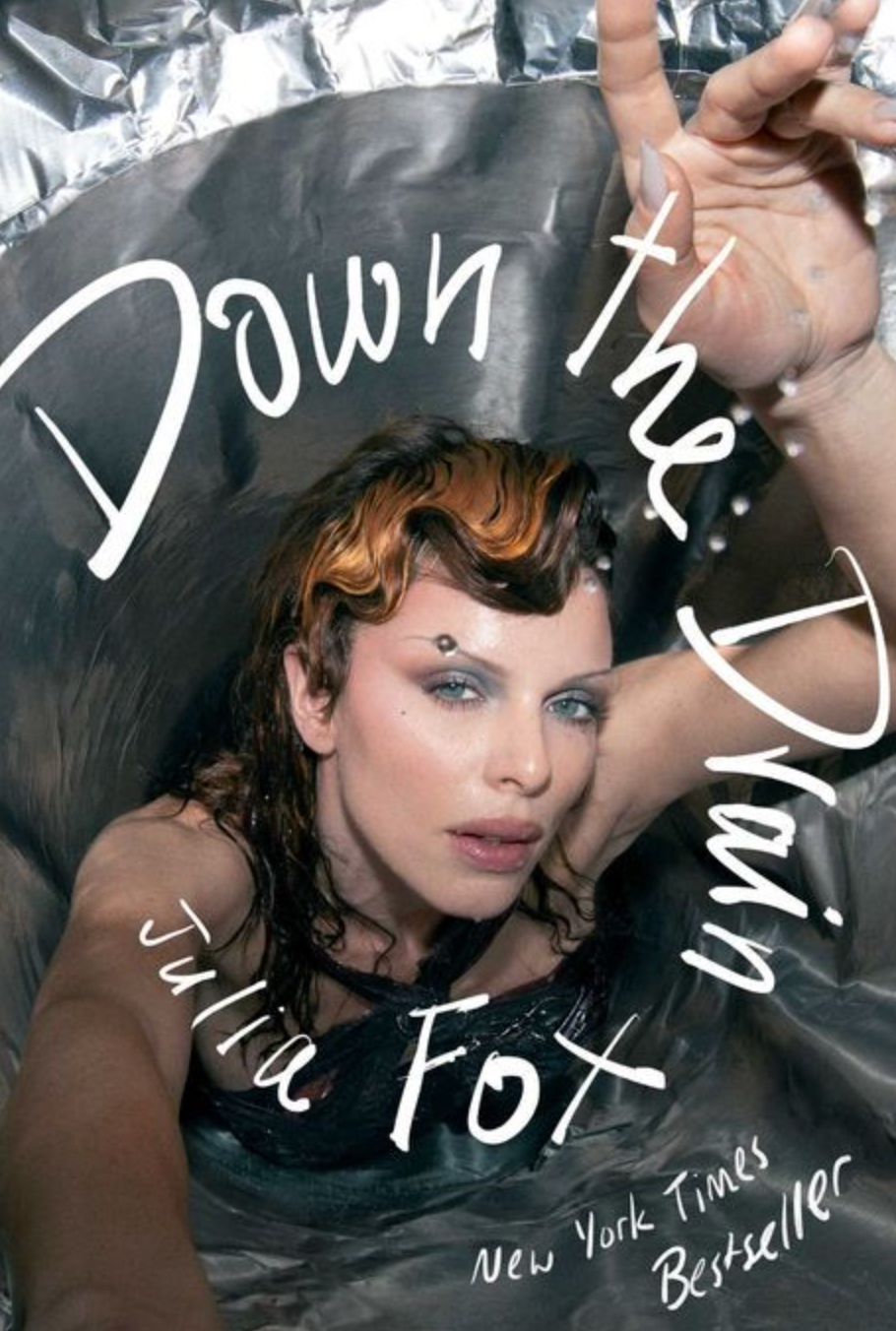 Book cover for "Down the Drain" by Julia Fox, featuring her reaching towards the camera with wet hair. Text notes it's a New York Times Bestseller