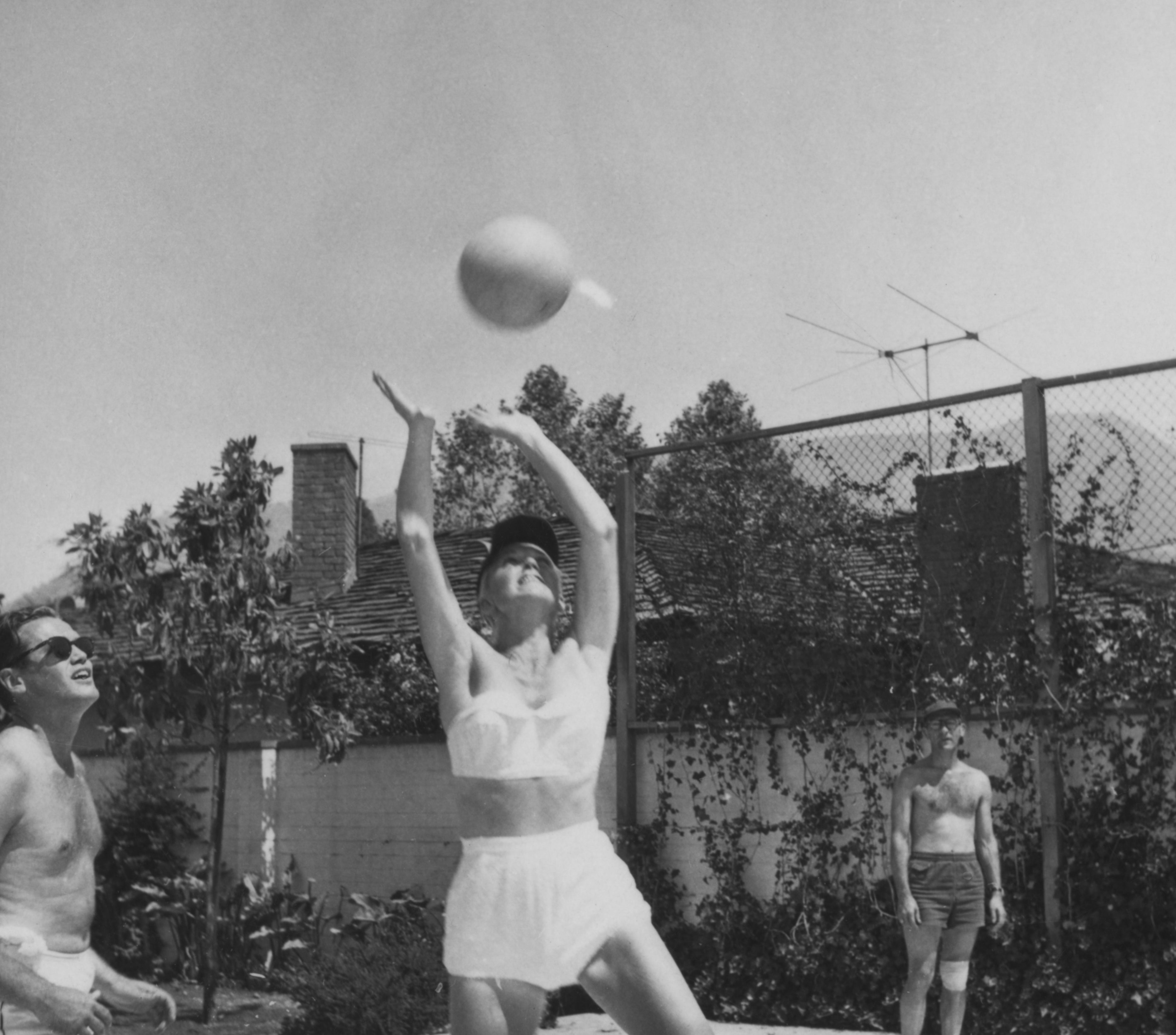 Doris Day and two men play volleyball outdoors.
