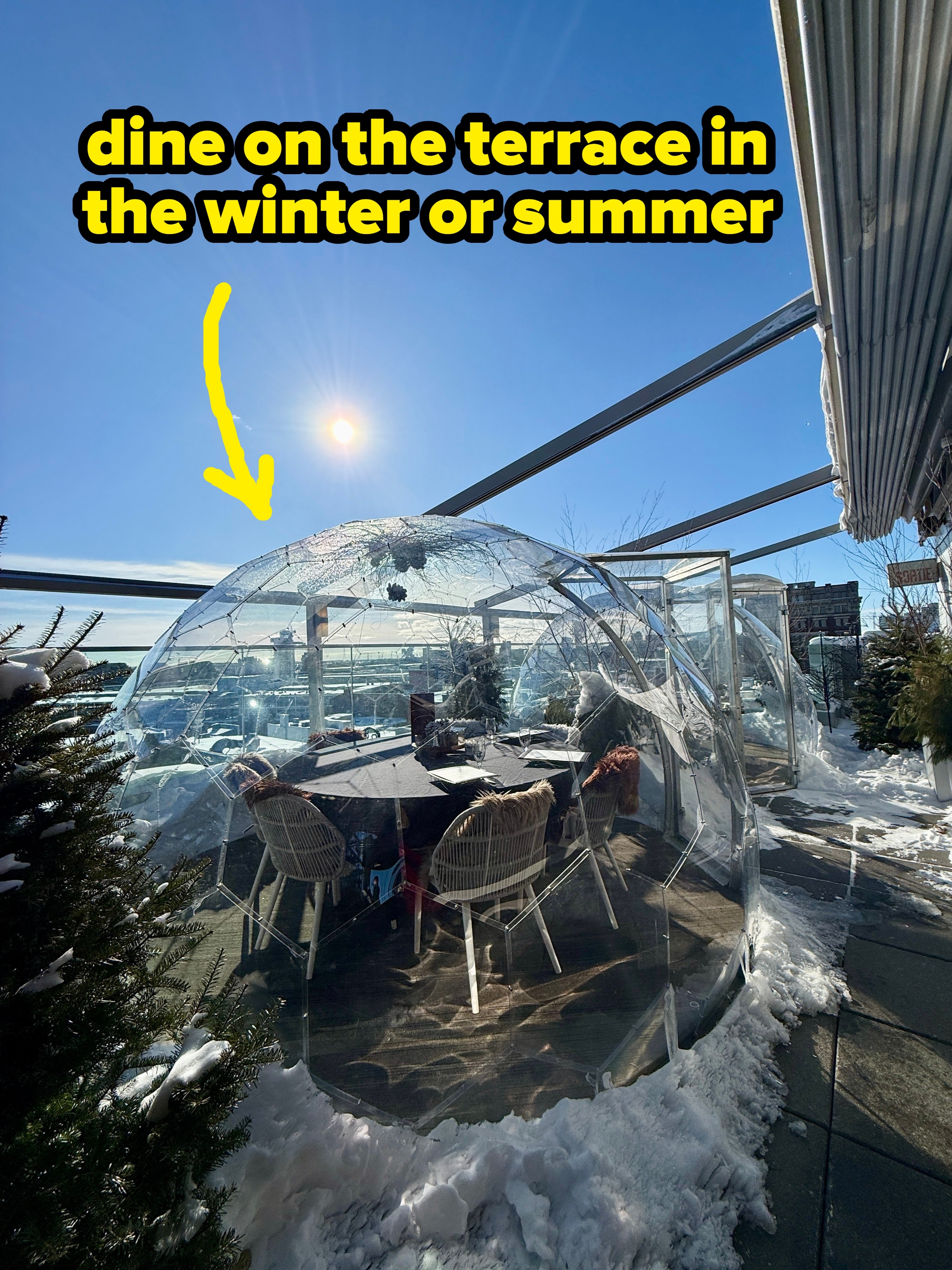 Transparent eating dome connected a rooftop terrace with chairs and a array inside, surrounded by snow, nether a wide bluish sky