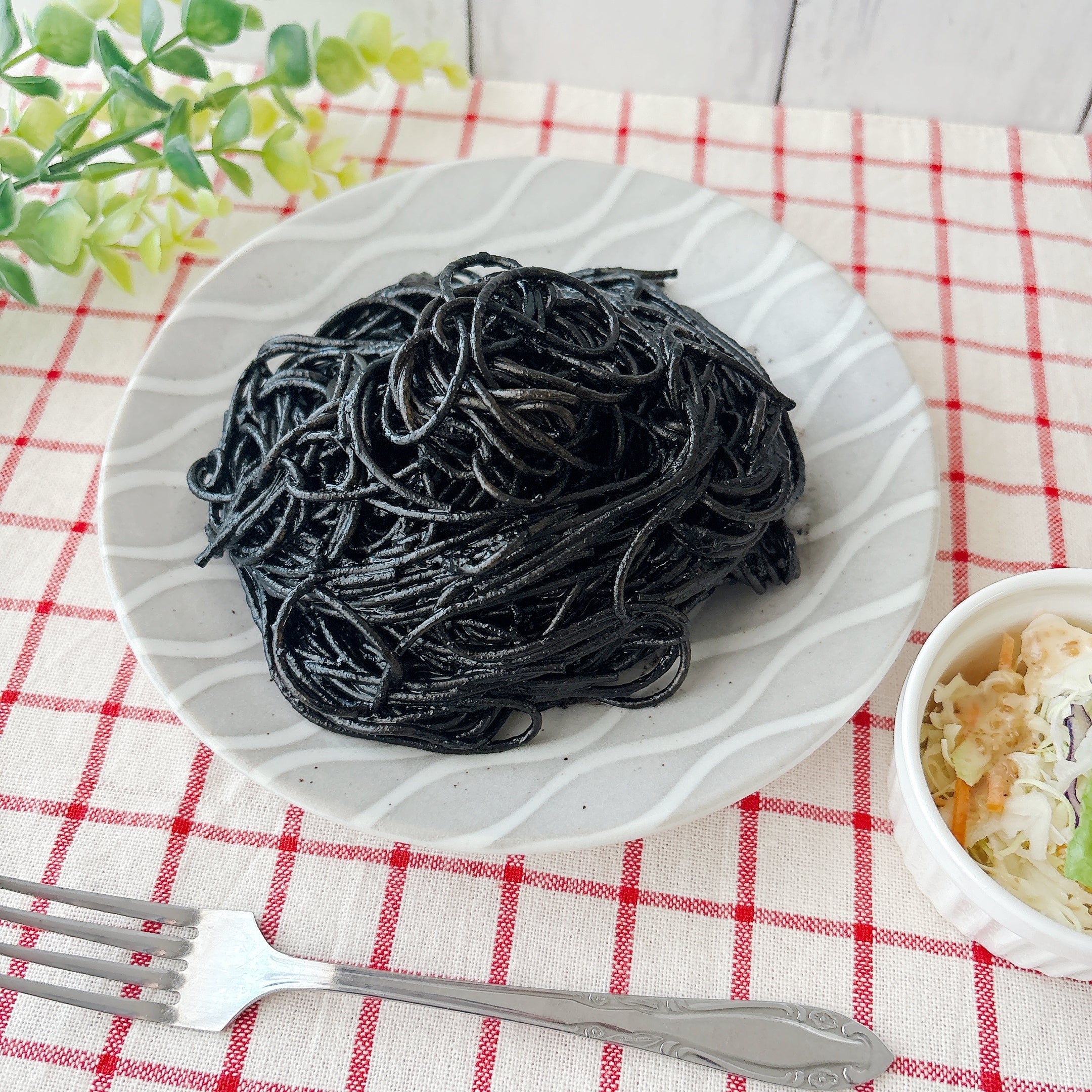 無印良品の「あえるだけのパスタソース いかすみ」皿に盛られたいかすみパスタと、サイドにコールスローサラダが添えられた食事。