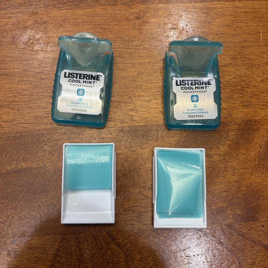 Two Listerine PocketPaks with mint strips, 1  full, 1  half-empty, connected  a woody  surface