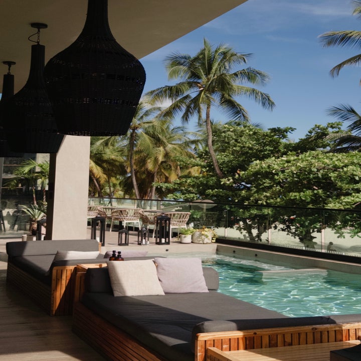 Outdoor seating by a pool with palm trees in the background, suggesting a tropical or vacation setting
