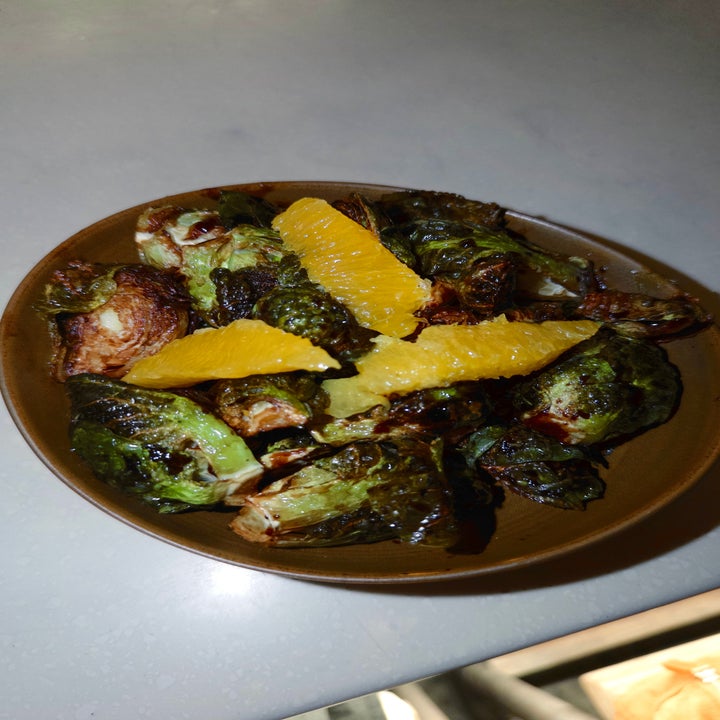 Roasted Brussels sprouts in a bowl, topped with slices of orange