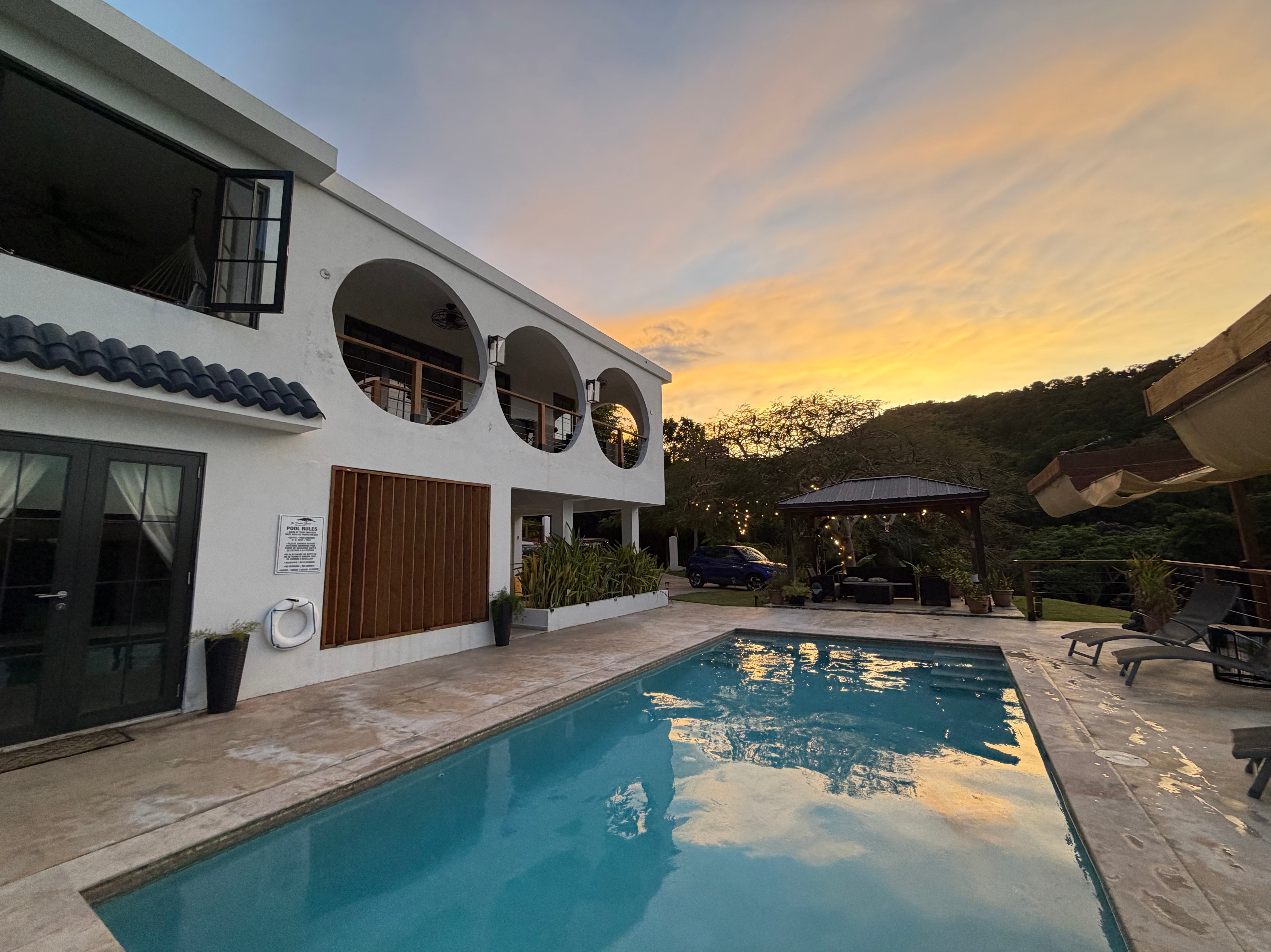 Luxurious outdoor pool and modern villa with arched windows at sunset, offering a serene and elegant atmosphere