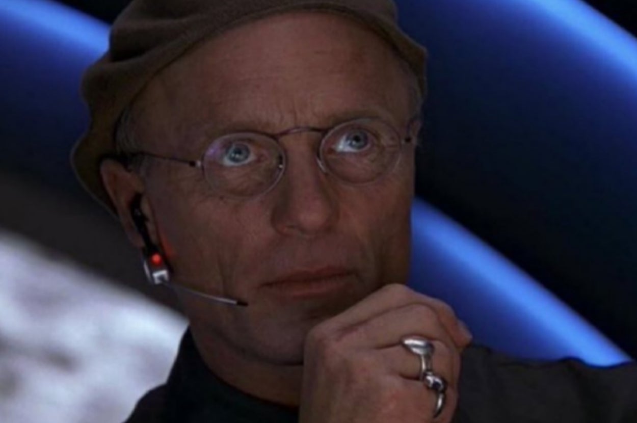 Person wearing a headset and glasses indoors, with a thoughtful expression and a hat