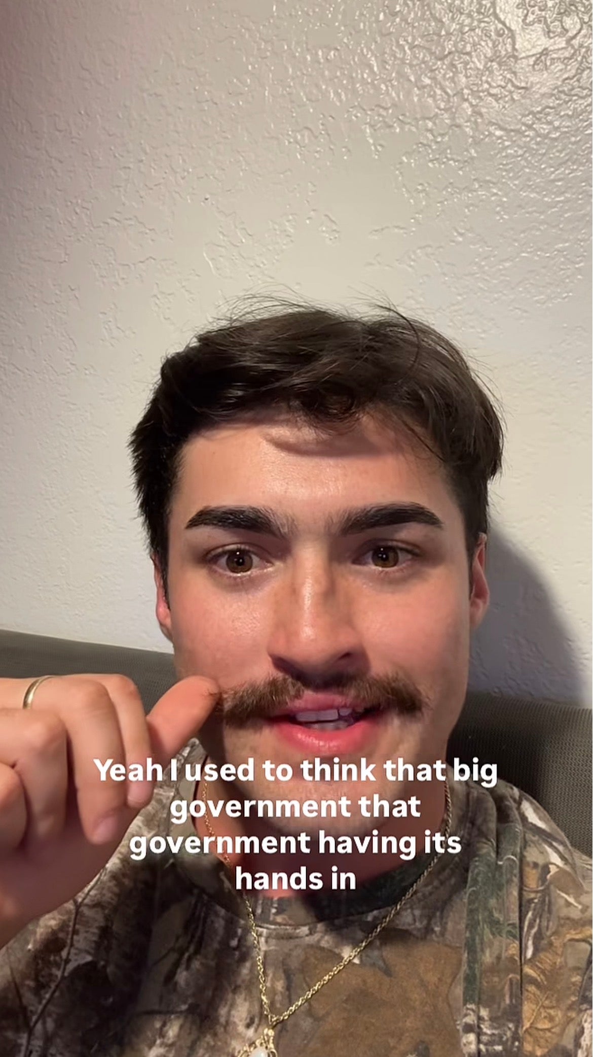 Man with a mustache in camouflage shirt speaking, text overlay reads, "Yeah I used to think that big government that government having its hands in."