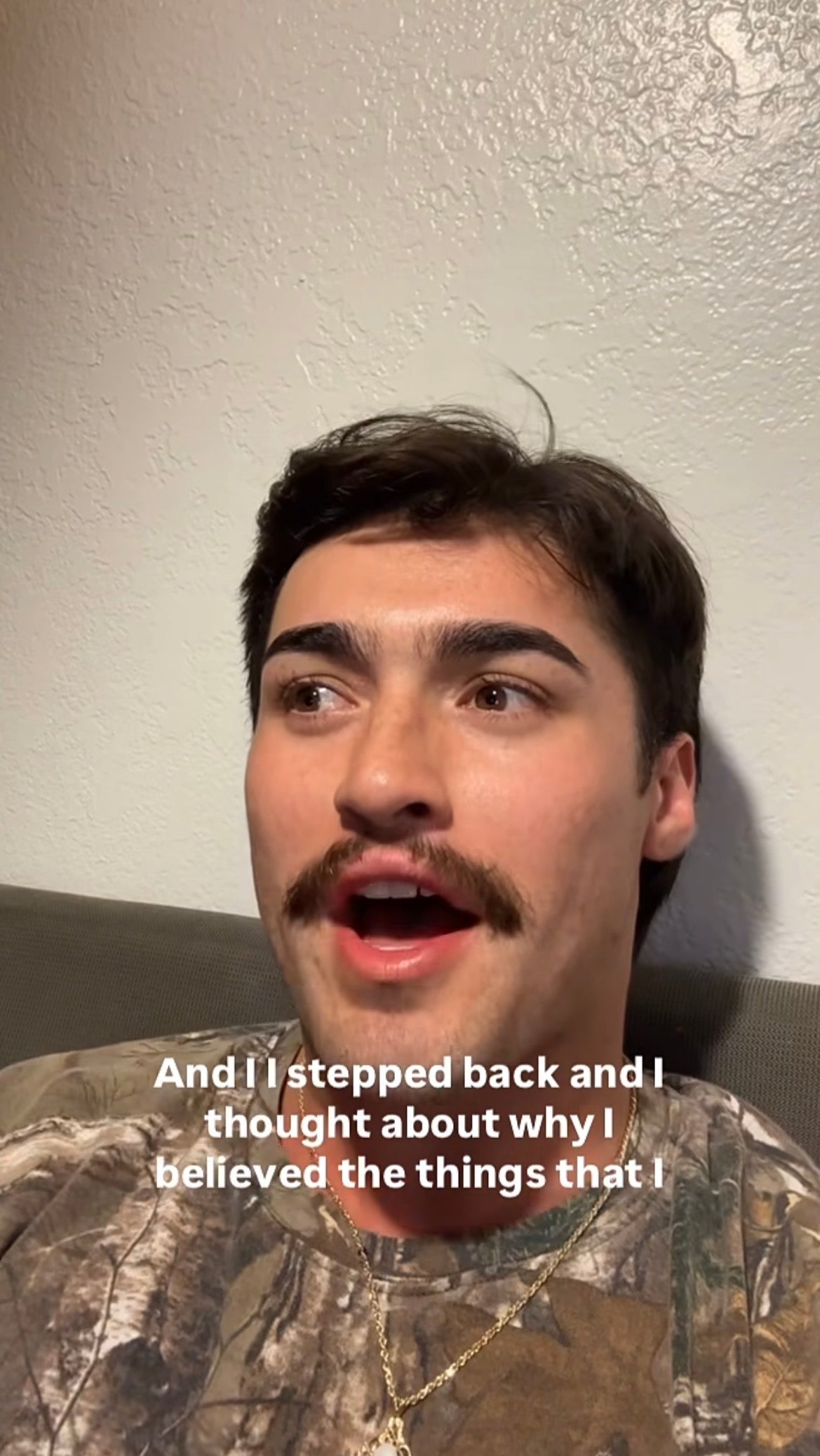 Person with a mustache, wearing a camouflage-patterned shirt, speaking. Subtitle reads: "And I stepped back and I thought about why I believed the things that I..."