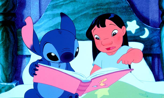 Lilo dan Stitch duduk di tempat tidur sambil membaca buku besar bersama, tampak bertunangan dan penasaran