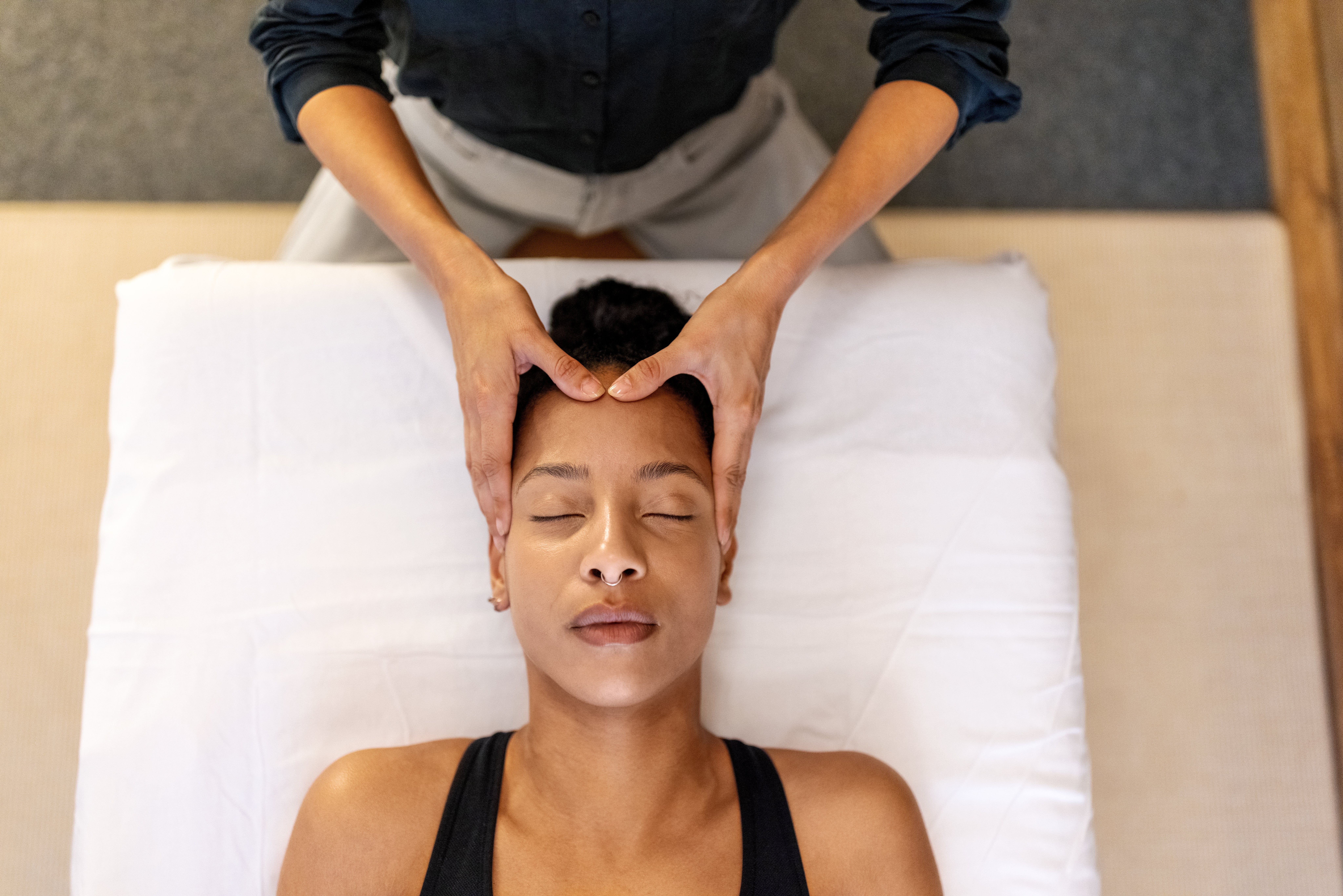 Person receiving a relaxing facial massage while lying on a massage table with their eyes closed