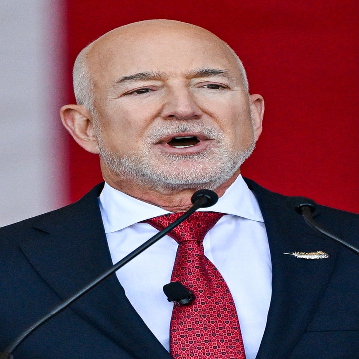 Man in a suit and red tie speaking at an event