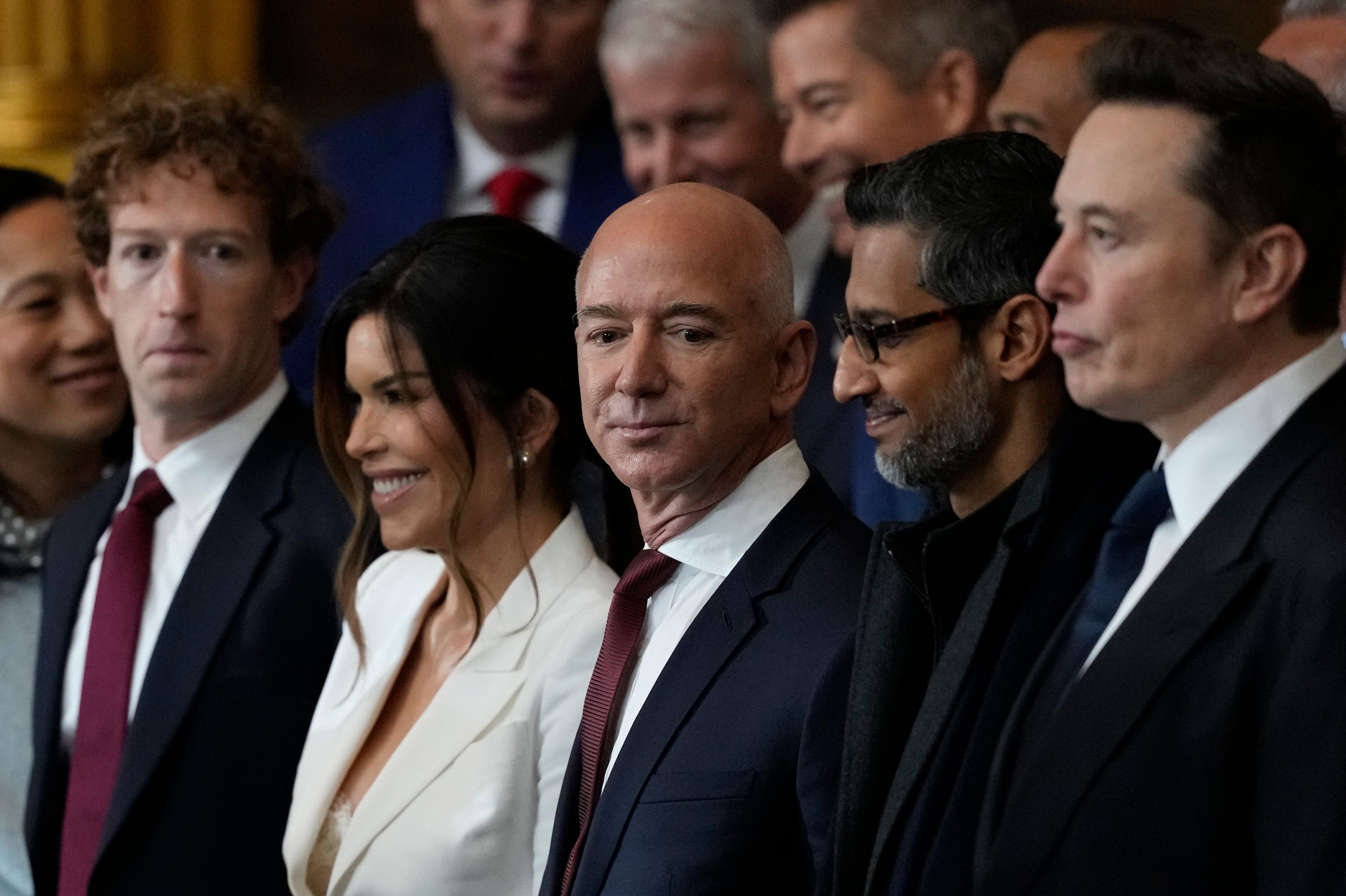 Group of executives in formal attire at an event, including individuals in suits and dresses, engaged in conversation