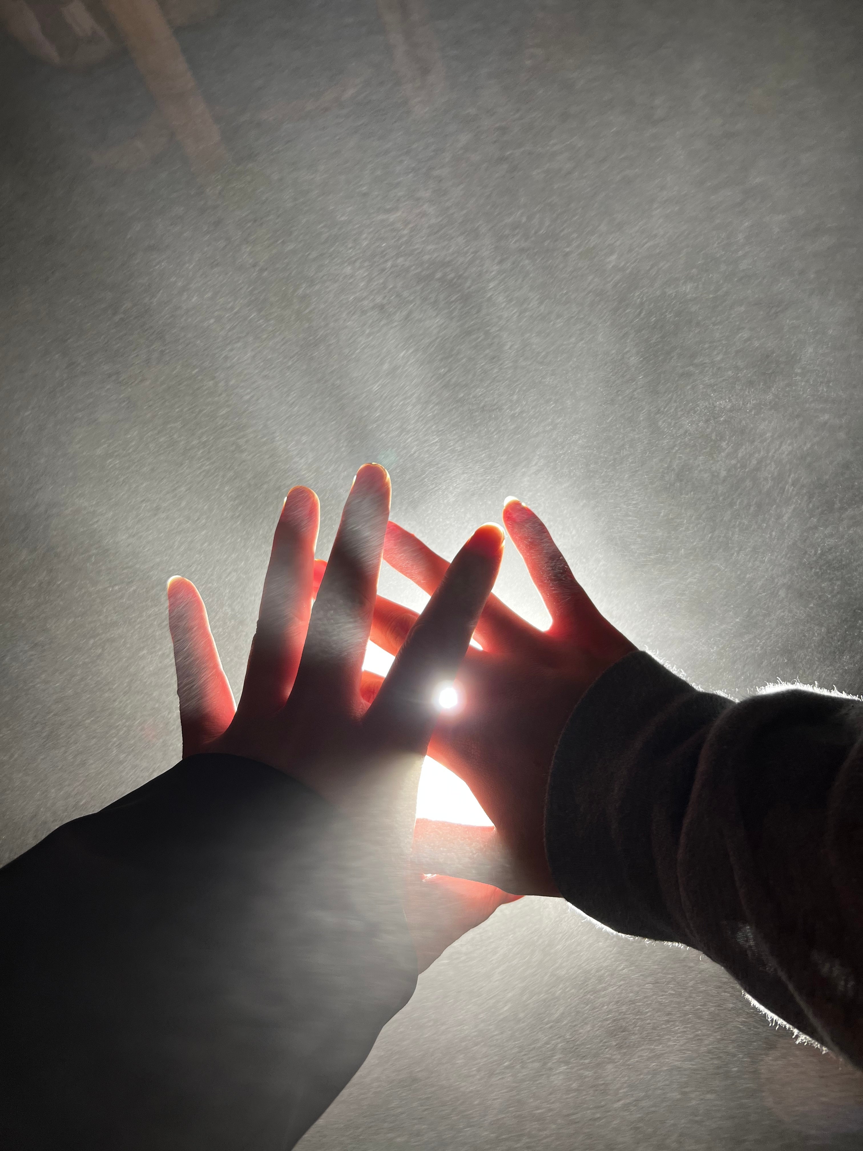 Two hands covering a bright light, causing a glow effect
