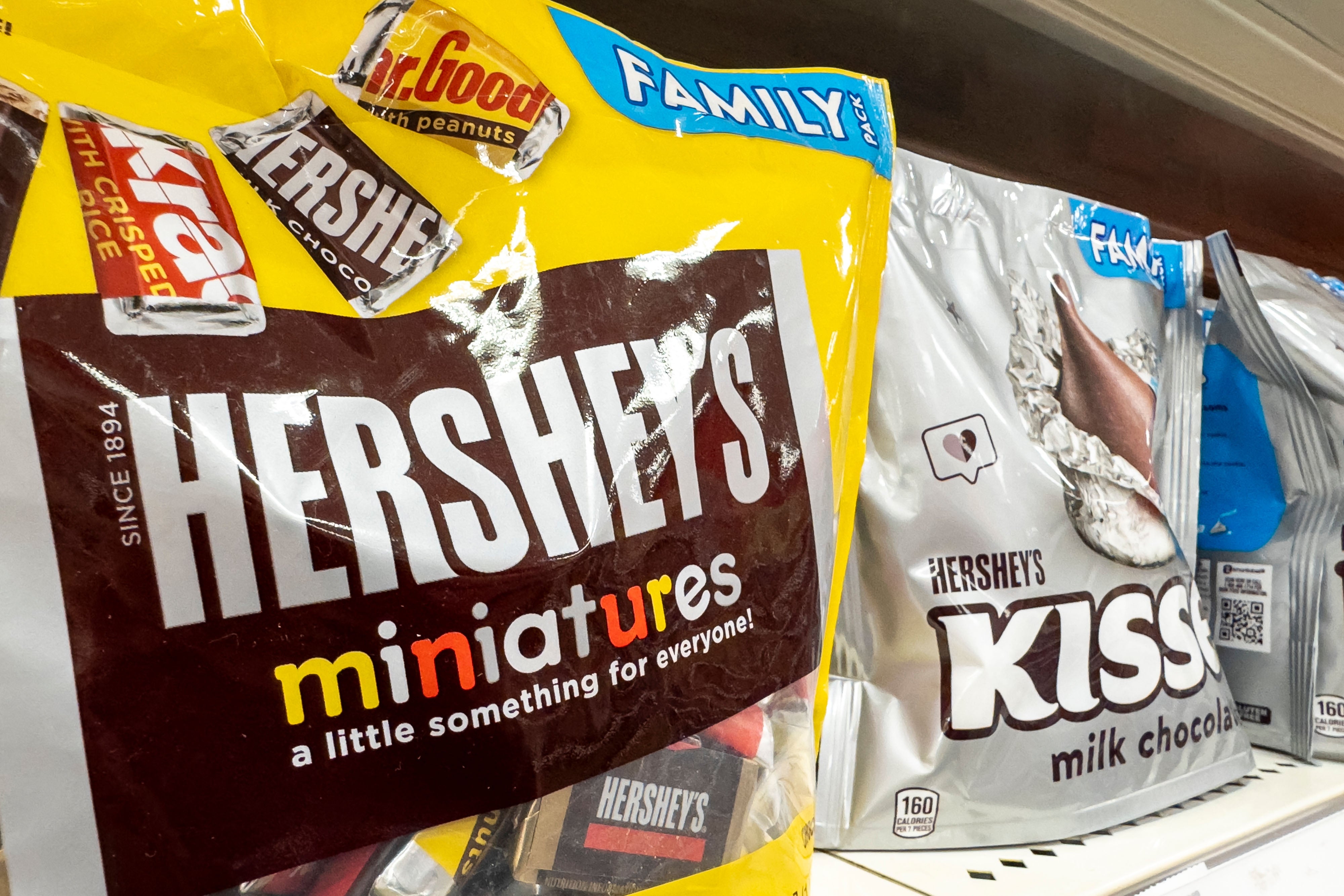 Bags of Hershey's miniatures and kisses are displayed on a store shelf, highlighting candy options for consumers