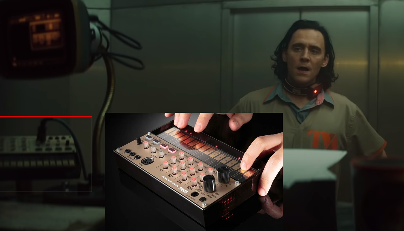 A person with shoulder-length hair stands in a room wearing a prison jumpsuit and a collar device, next to an inset of hands using a small electronic music device