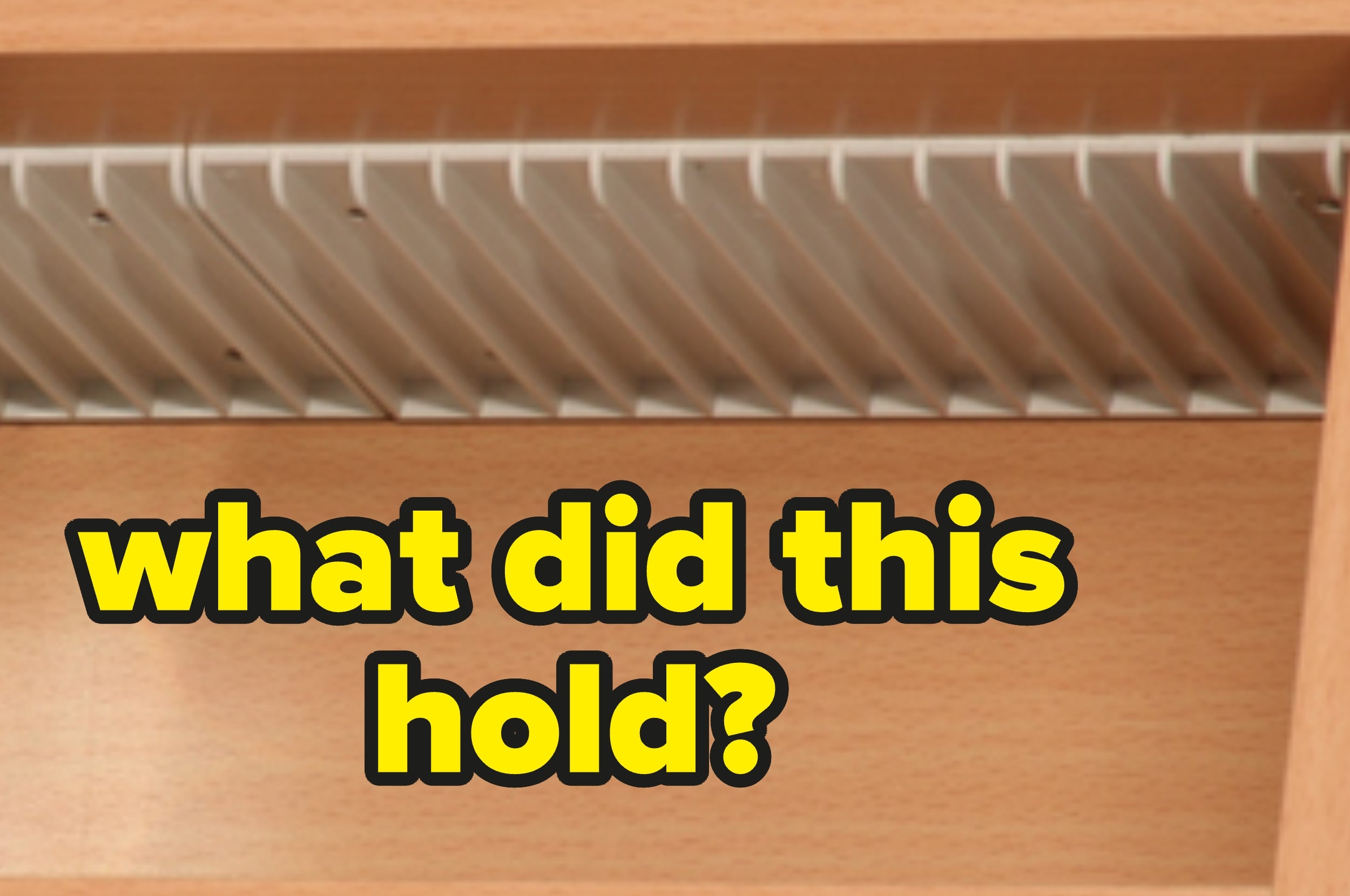 Empty vertical dish rack inside a wooden cabinet with bold text asking, "what did this hold?"