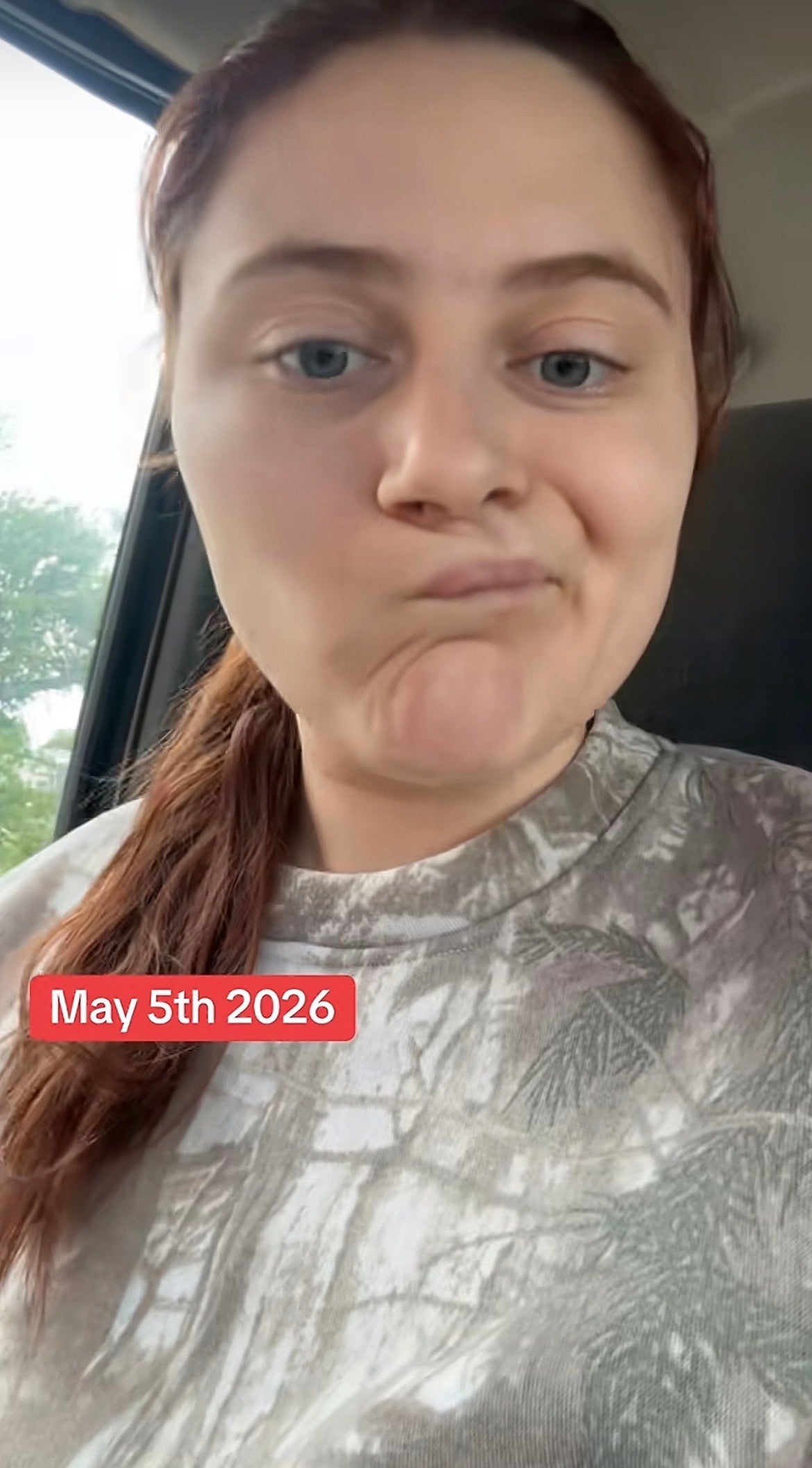 Person with long hair wearing a camo shirt. Overlay text reads: "May 5th 2026."