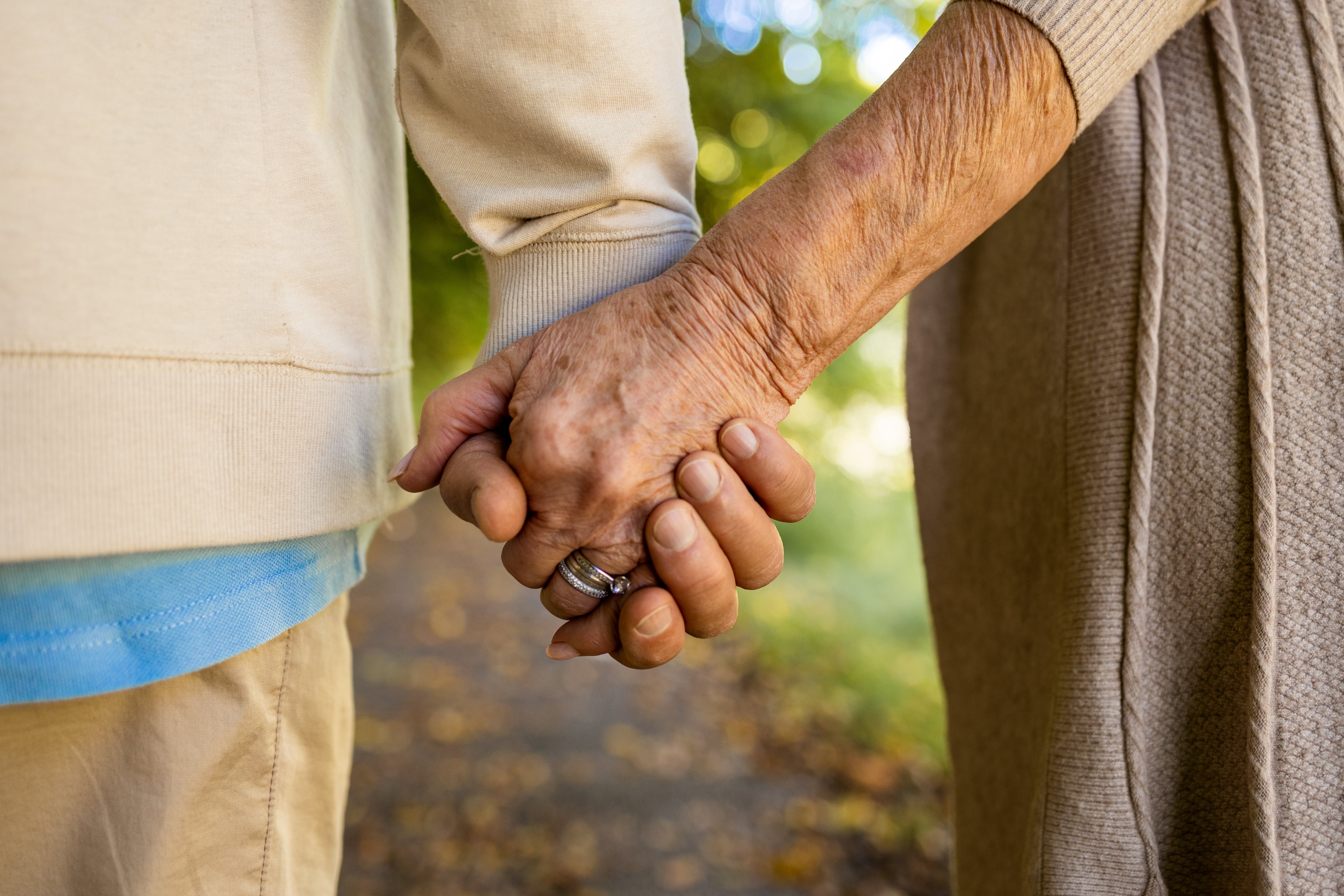 Elderly couple holding hands while walking outdoors on a sunny day